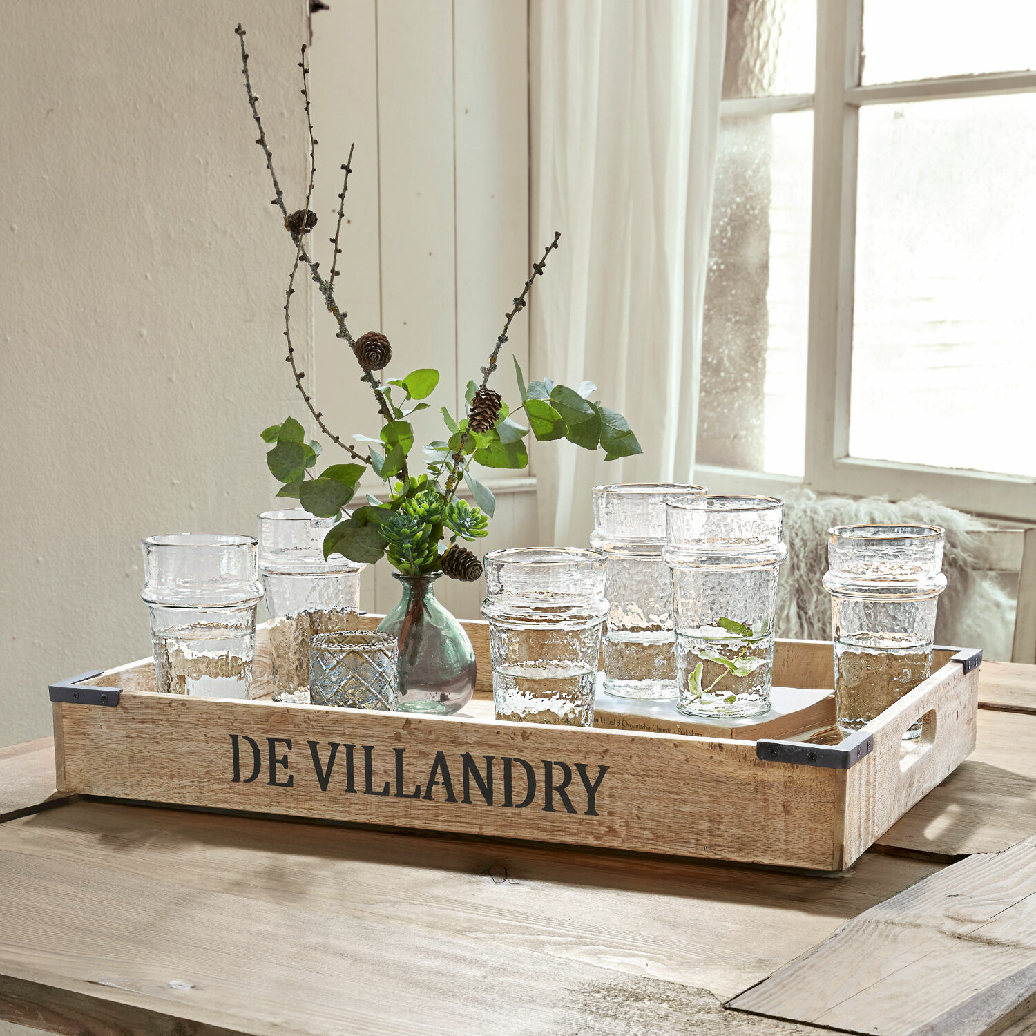 Holztablett DE VILLANDRY mit klaren Gläsern und grünen Zweigen auf hellem Holztisch