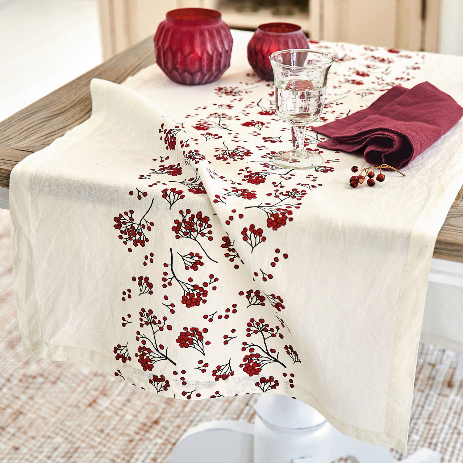 Tischläufer Vestré Leinen-Tischdecke in Creme mit rotem Beerenmuster auf Holztisch mit Dekorationen