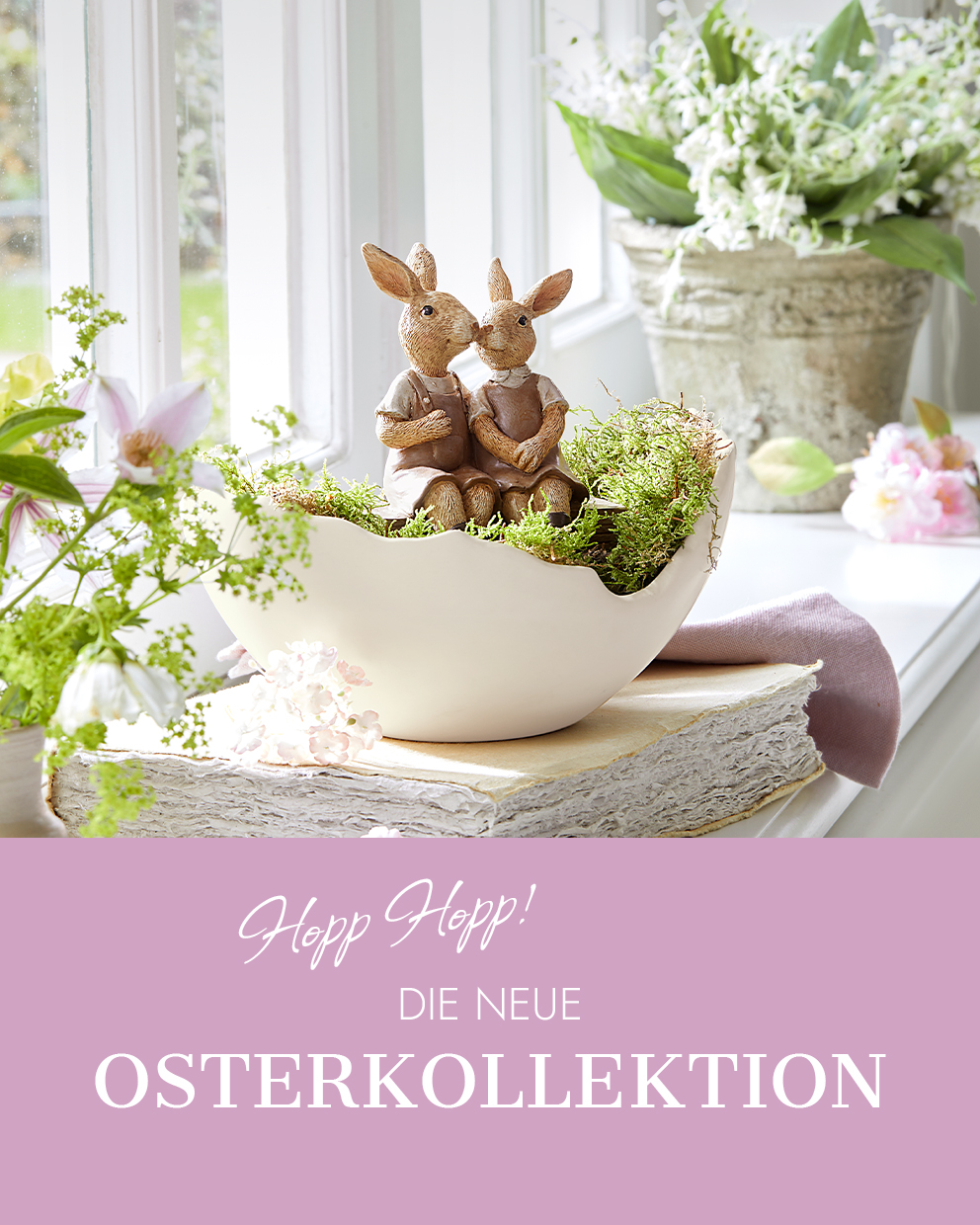Zwei Hasenfiguren aus Keramik in beiger Schale mit Moos als frühlingshafte Osterdekoration