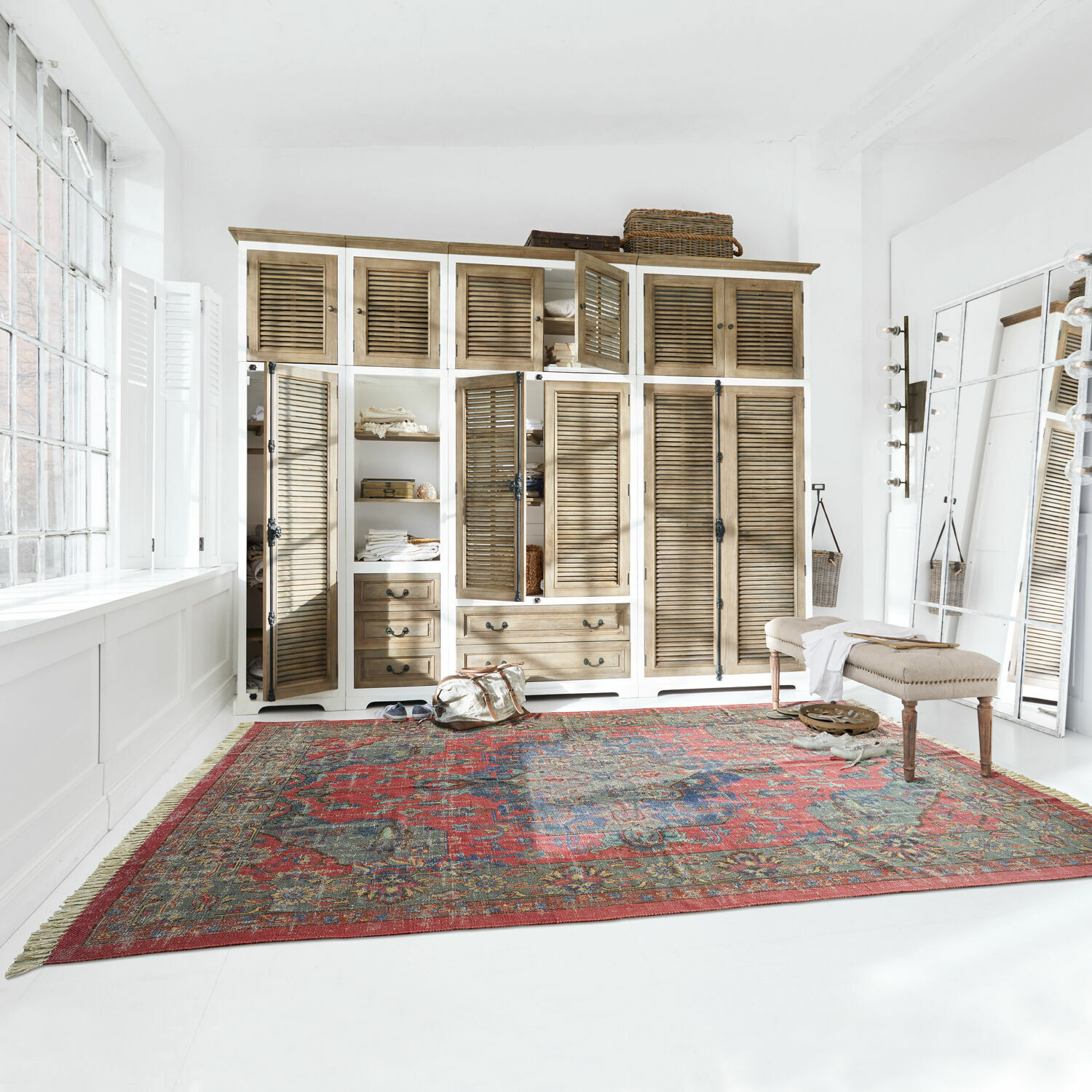 Großer roter Teppich mit orientalischem Muster in hellem Raum mit Holzschrank und Bank