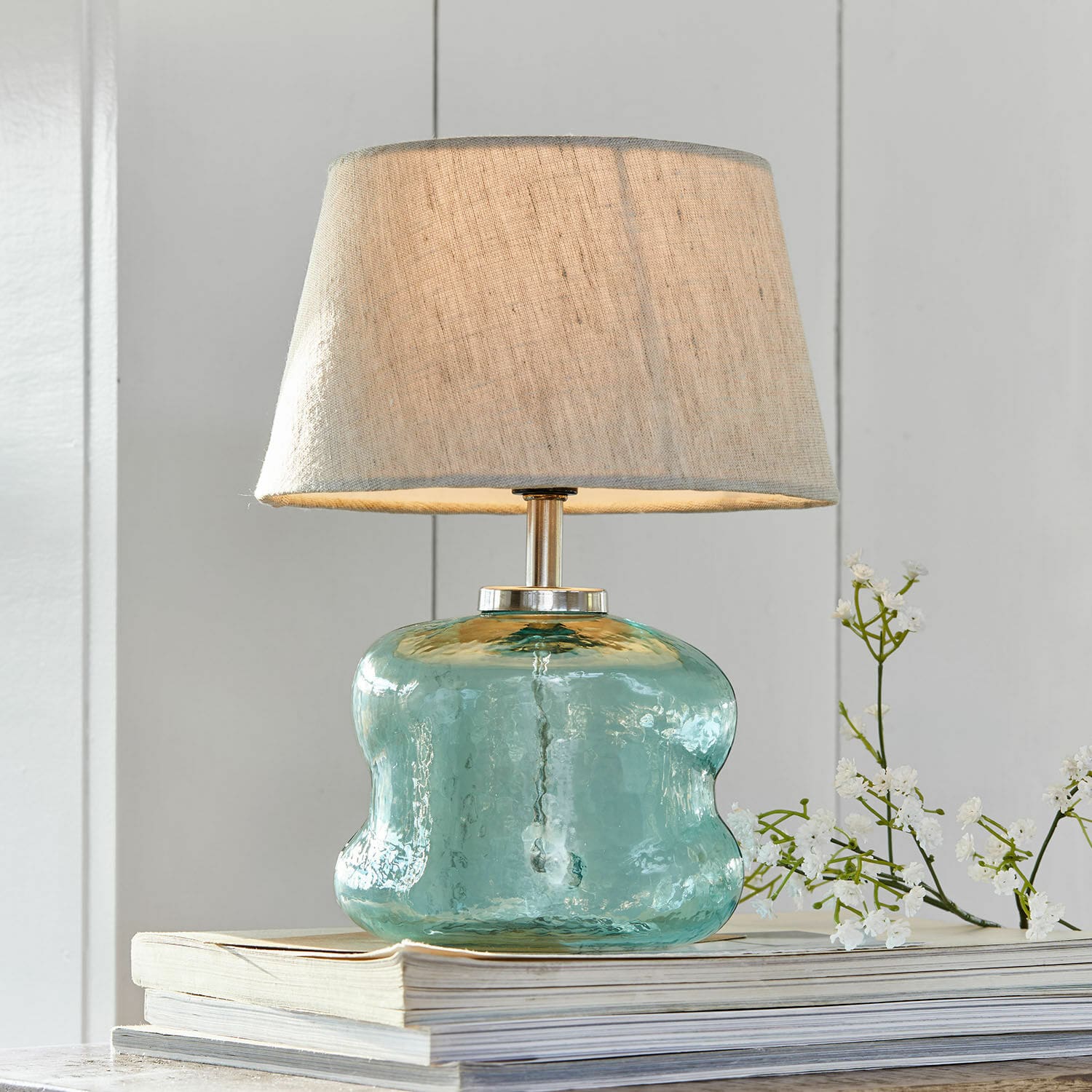 Tischlampe Rufino Tischlampe aus blauem Glas mit beigem Lampenschirm auf Bücherstapel, Wohnaccessoire