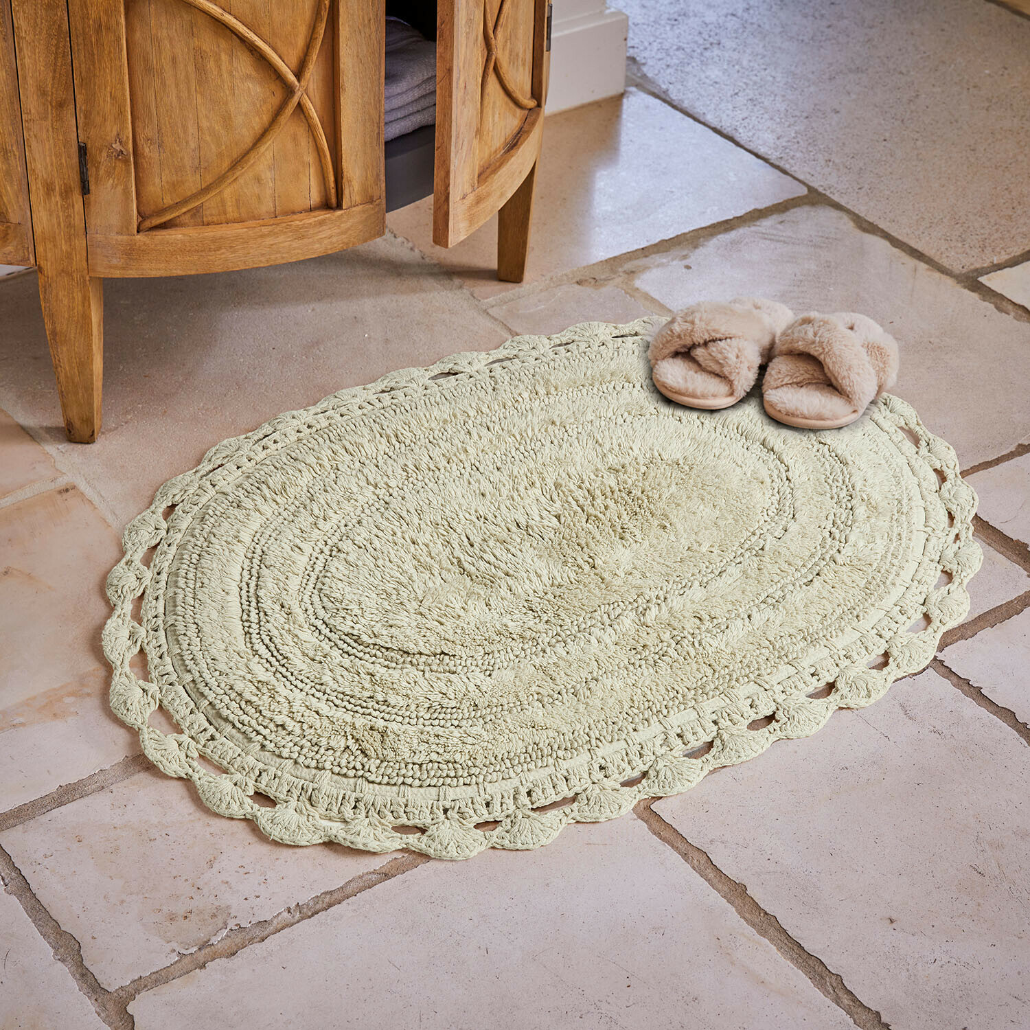 Ovaler Baumwollteppich in hellem Beige mit dekorativem Rand auf Steinboden