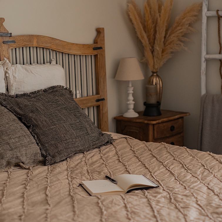 Gemütliches Schlafzimmer mit Holzbett und beiger Bettdecke, Boho-Dekorationen