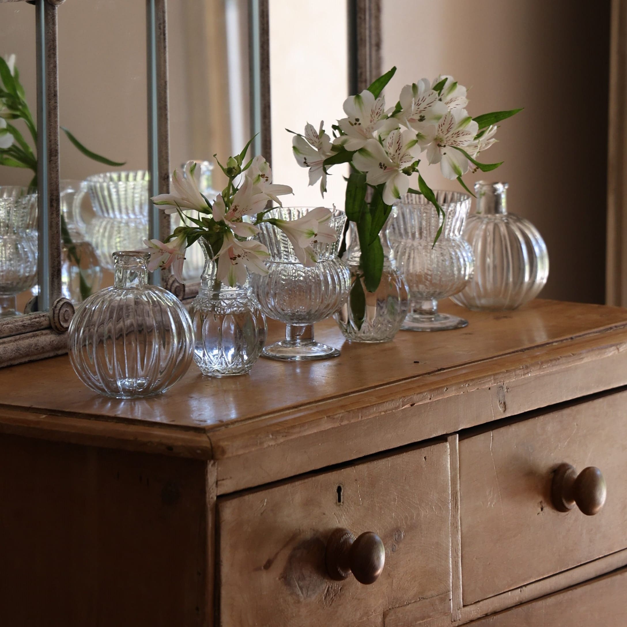 Transparente Glasvasen mit weißen Blumen auf vintage Holzkommode dekoriert