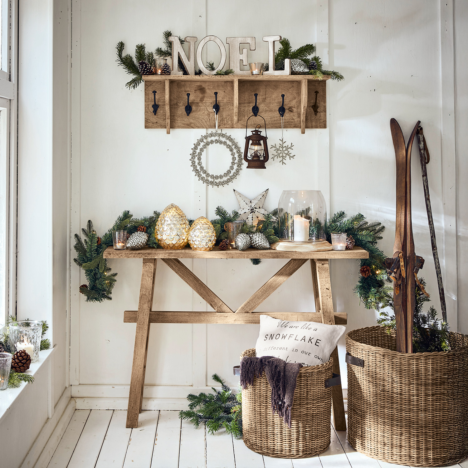 Holztisch und Garderobe mit Weihnachtsdeko, Laterne und Korb mit Skiern aus Weide
