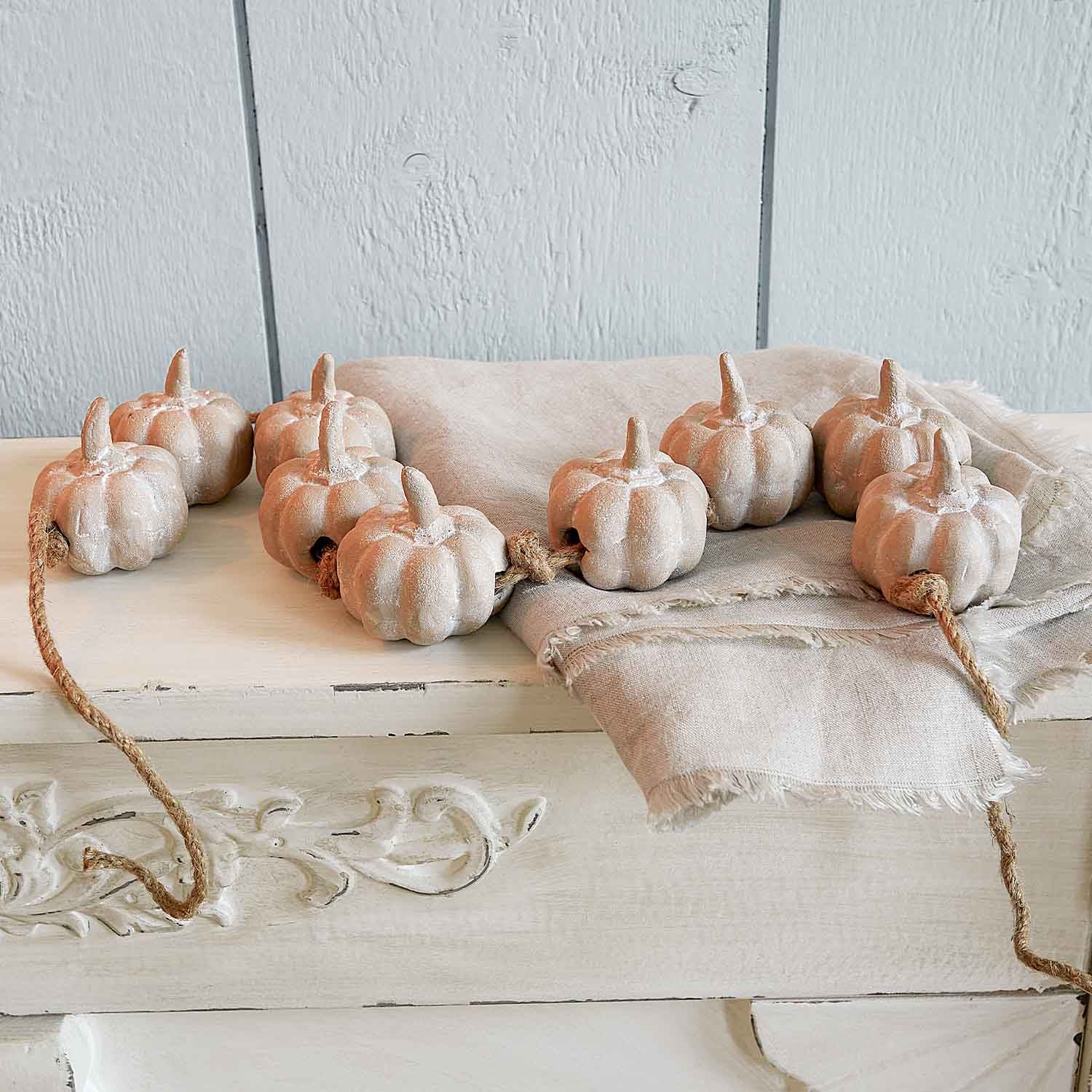 Dekorative Kette aus beigen Keramik-Kürbissen an Kordel für herbstliche Wohnaccessoires