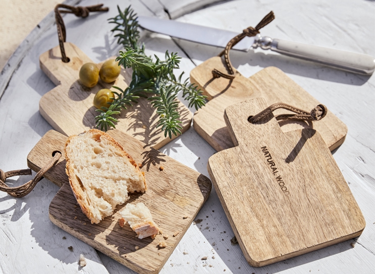 Set aus natürlichen Holz-Schneidebrettern mit Brot und Oliven auf weißem Tisch im mediterranen Stil