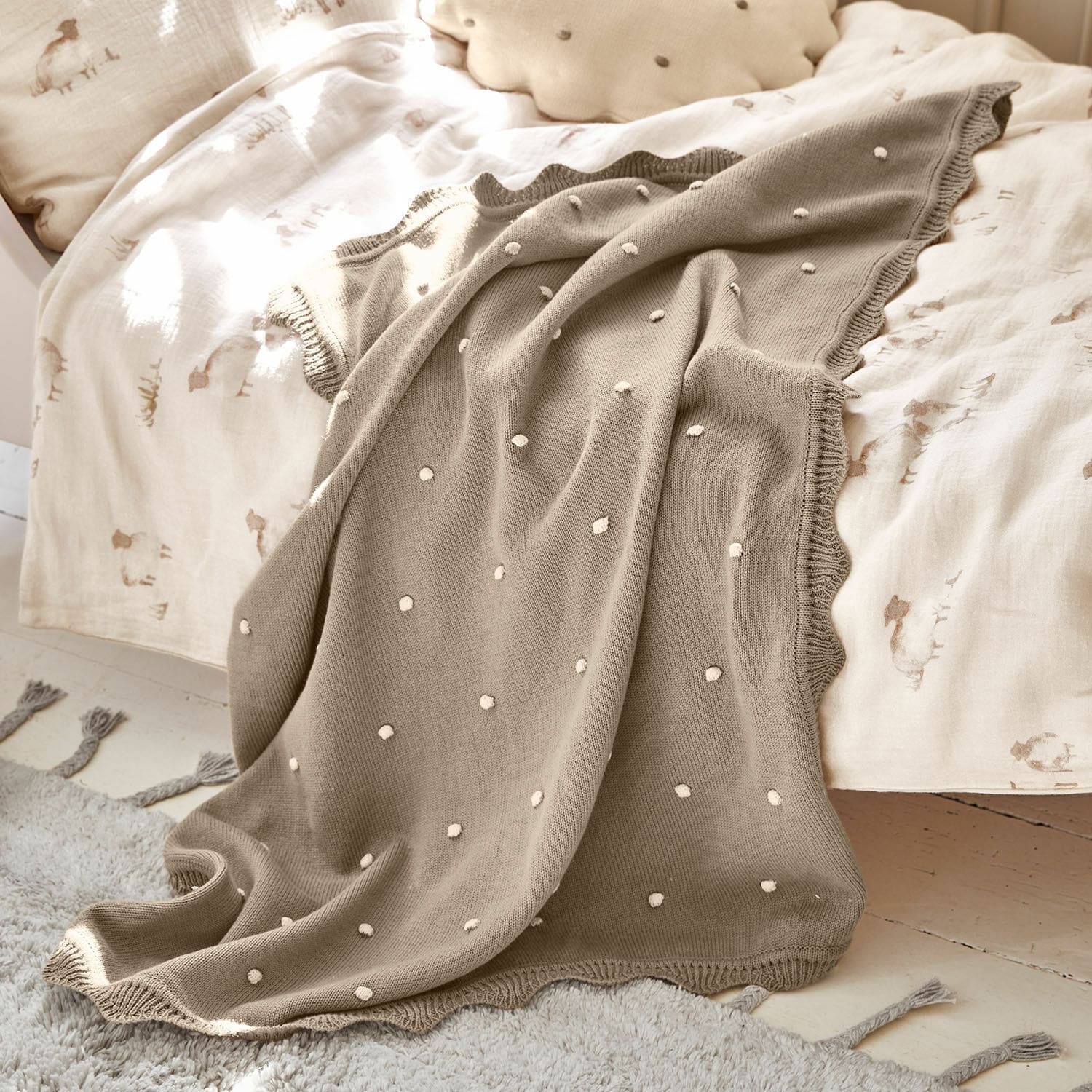 Plaid Saphie Beige gestrickte Decke mit weißen Punkten auf hellem Bett, weiche und dekorative Wohndecke