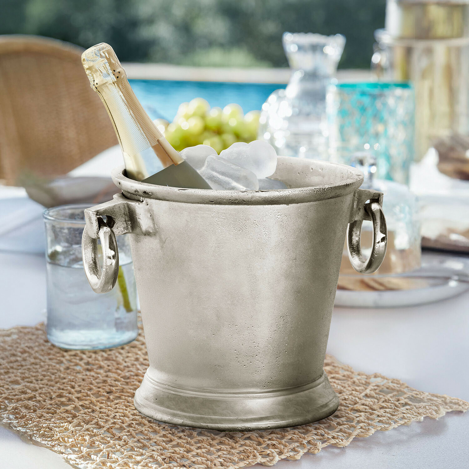 Getränkekühler Cressford Silbernes Metall-Eiswürfeleimer mit Champagnerflasche und Eis auf Gartentisch