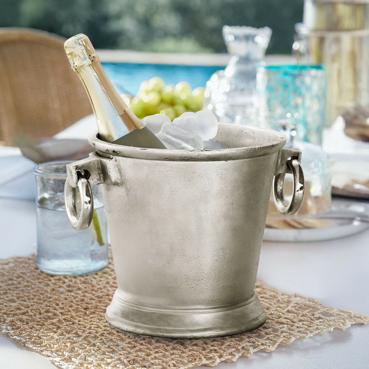 Getränkekühler Cressford Silbernes Metall-Eiswürfeleimer mit Champagnerflasche und Eis auf Gartentisch