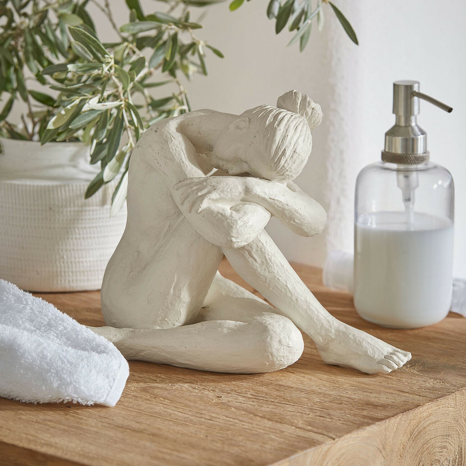 Figur Savigné Weiße Skulptur einer sitzenden Frau mit Kopf auf angewinkelten Knien auf Holzplatte im Badezimmer