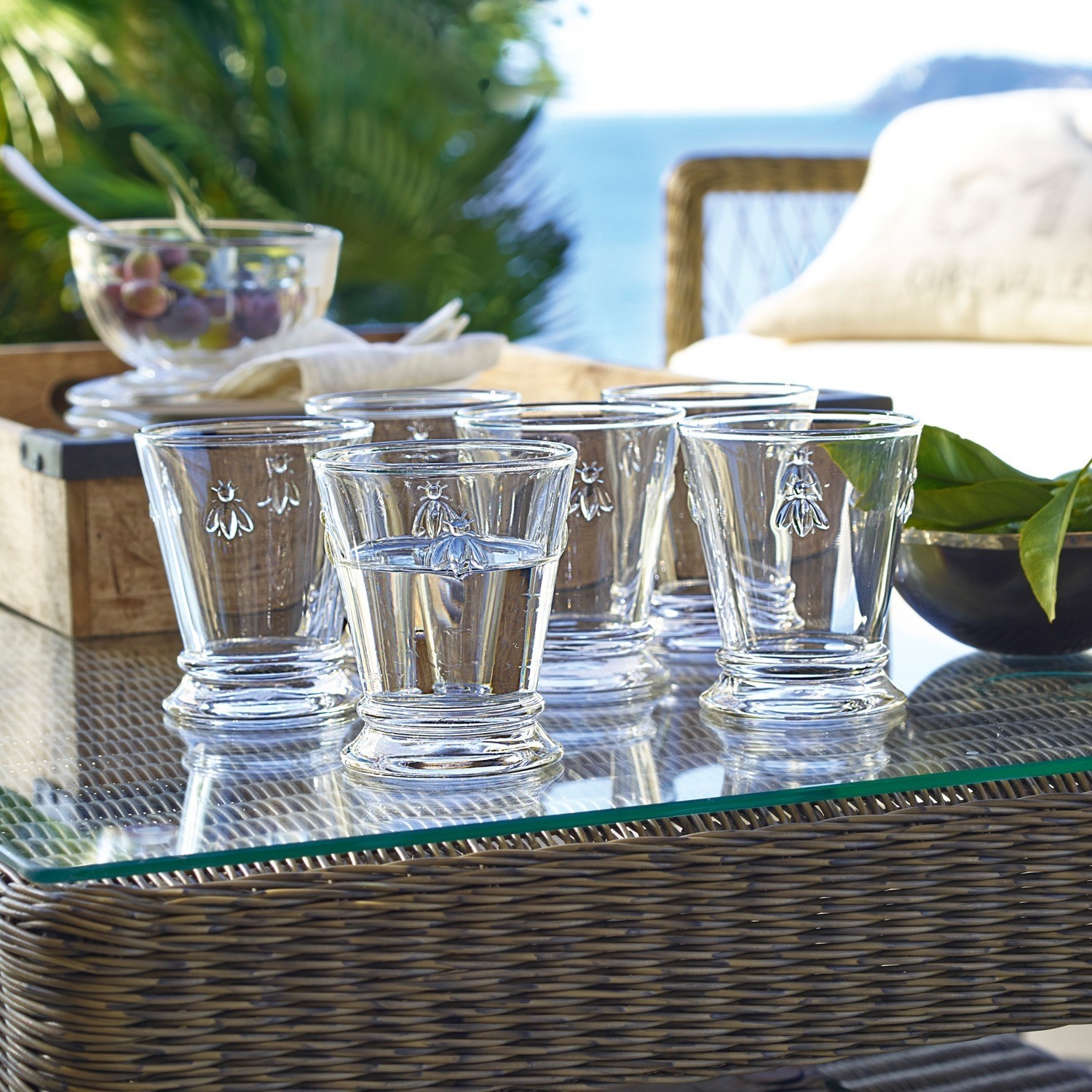 Wassergläser 6er Set Abeille Sechsteiliges Set aus klarem Glas mit Bienenmotiv auf Glastisch im Außenbereich