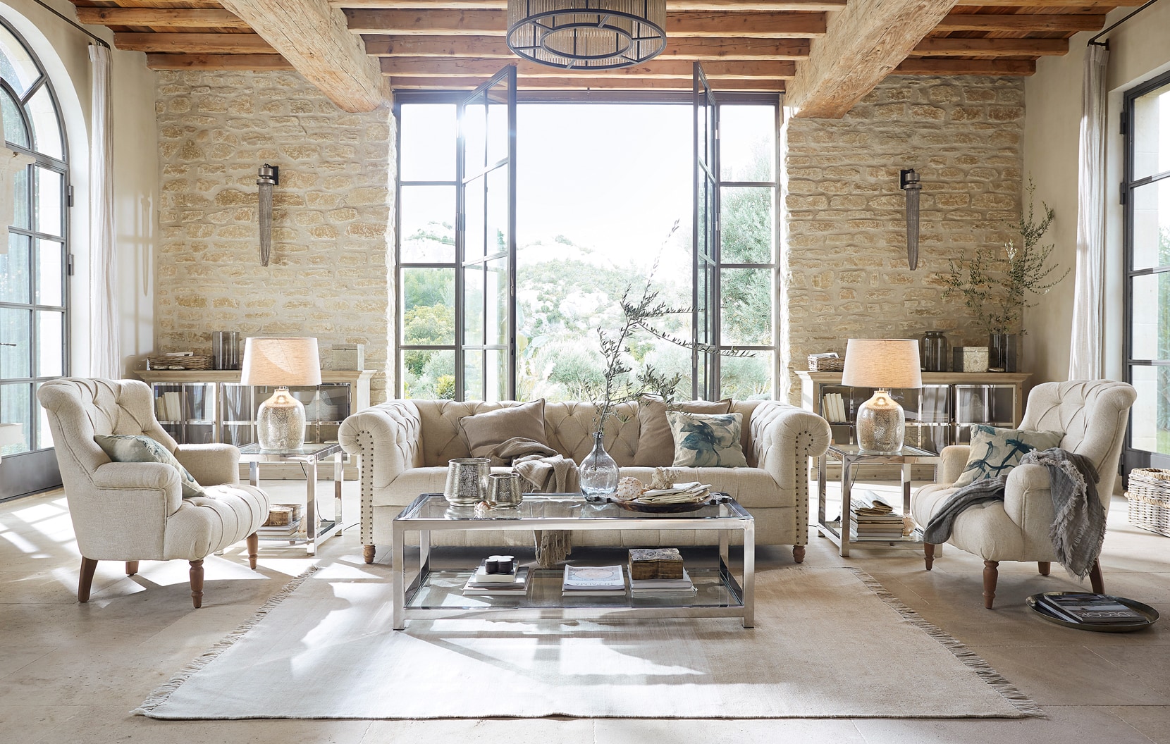 Klassisch elegantes Wohnzimmer mit beigem Sofa, Sesseln, Glastisch und natürlichen Materialien
