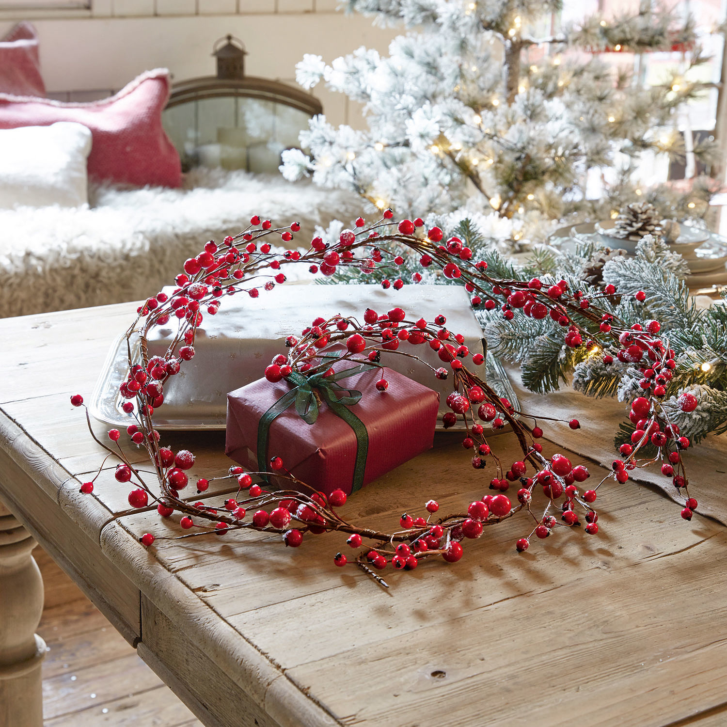 Girlande Rimont Dekorativer Kranz aus roten Beeren auf Holztisch mit Geschenk und Weihnachtsdeko