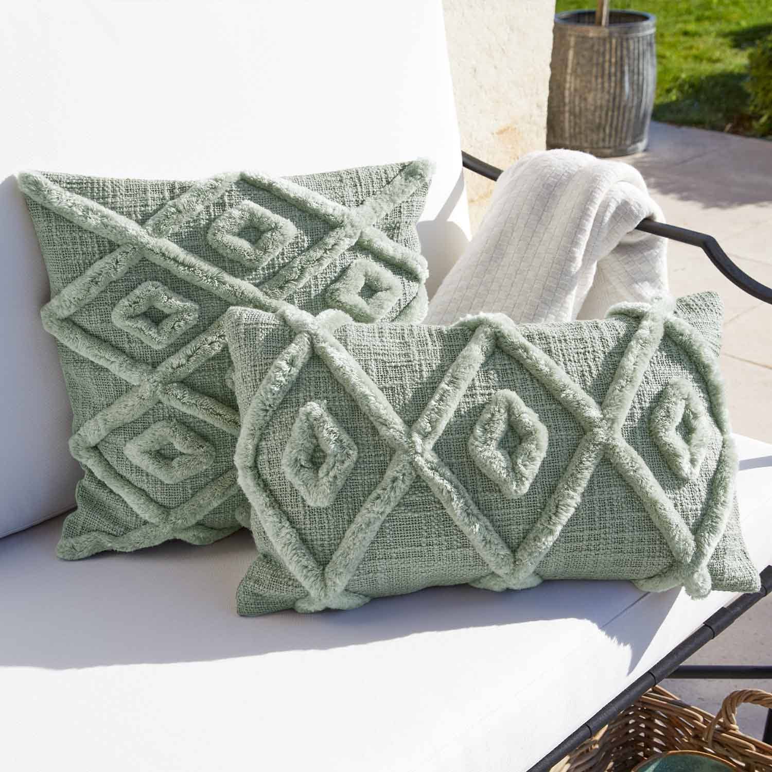Weiches grünes Dekokissen mit geometrischem Muster auf weißem Gartenstuhl