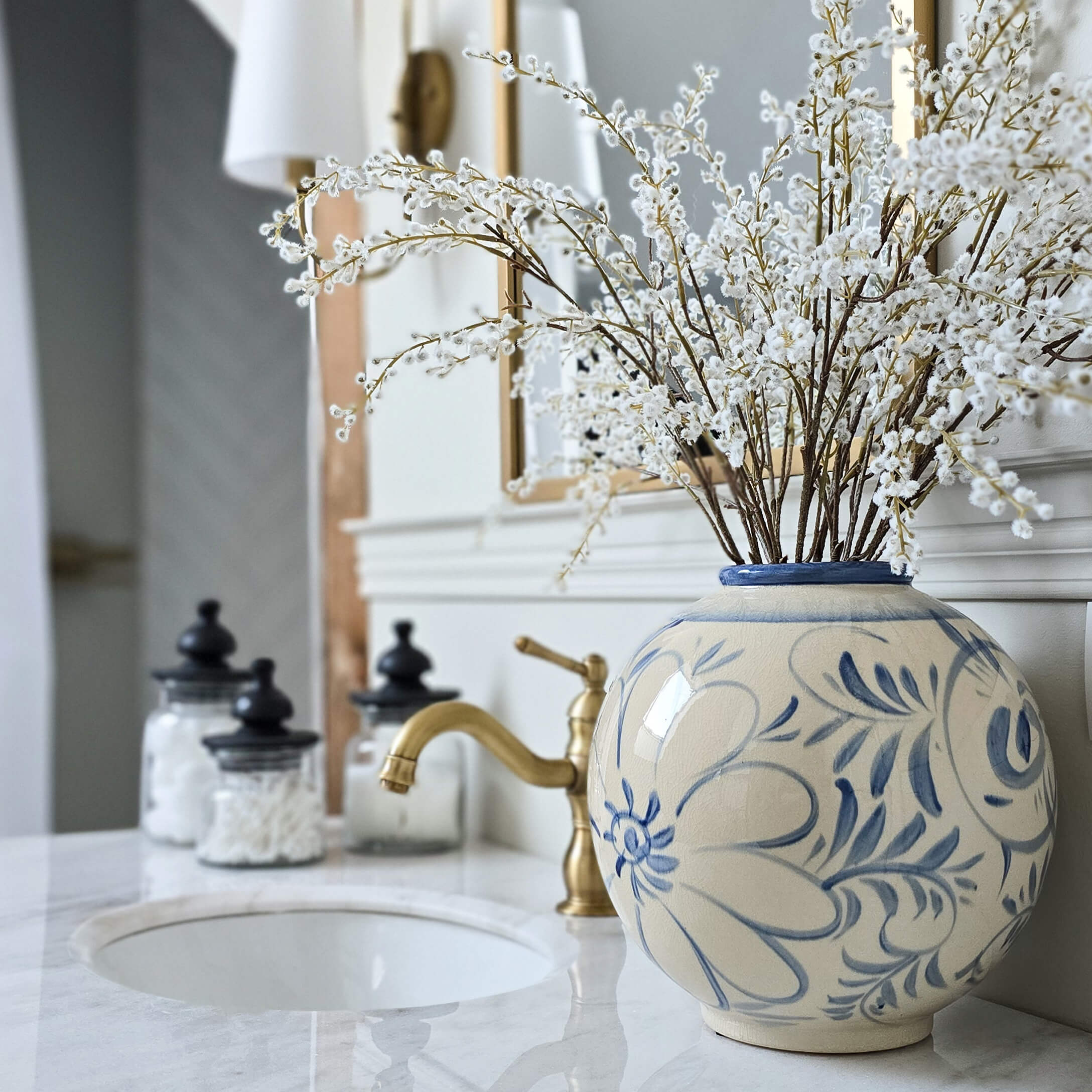 Runde Keramikvase mit blauem Blumenmuster auf Marmor-Waschbeckenablage mit Dekoration