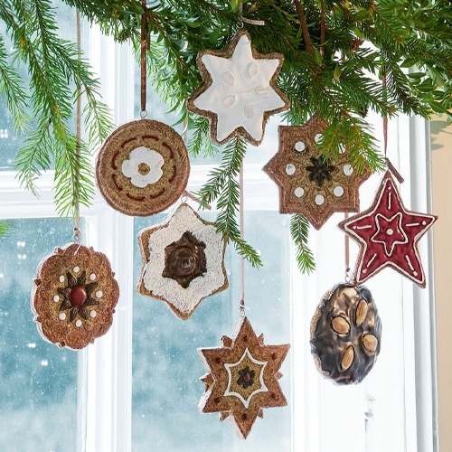 Weihnachtsschmuck aus natürlichen Materialien in Stern- und Kreisformen an Tannenzweig hängend
