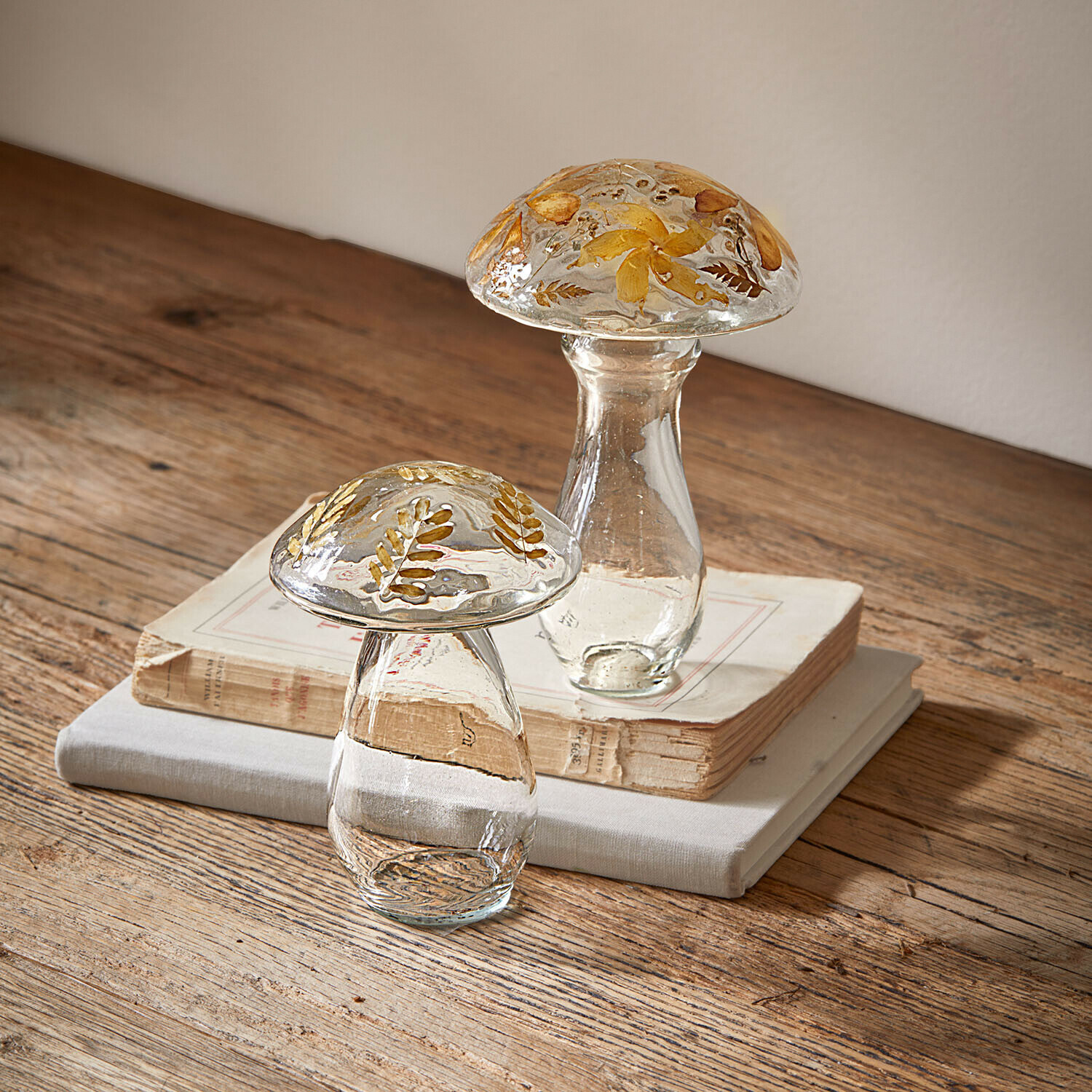 Glasdekorationen in Pilzform mit getrockneten gelben Blumen auf Holztisch