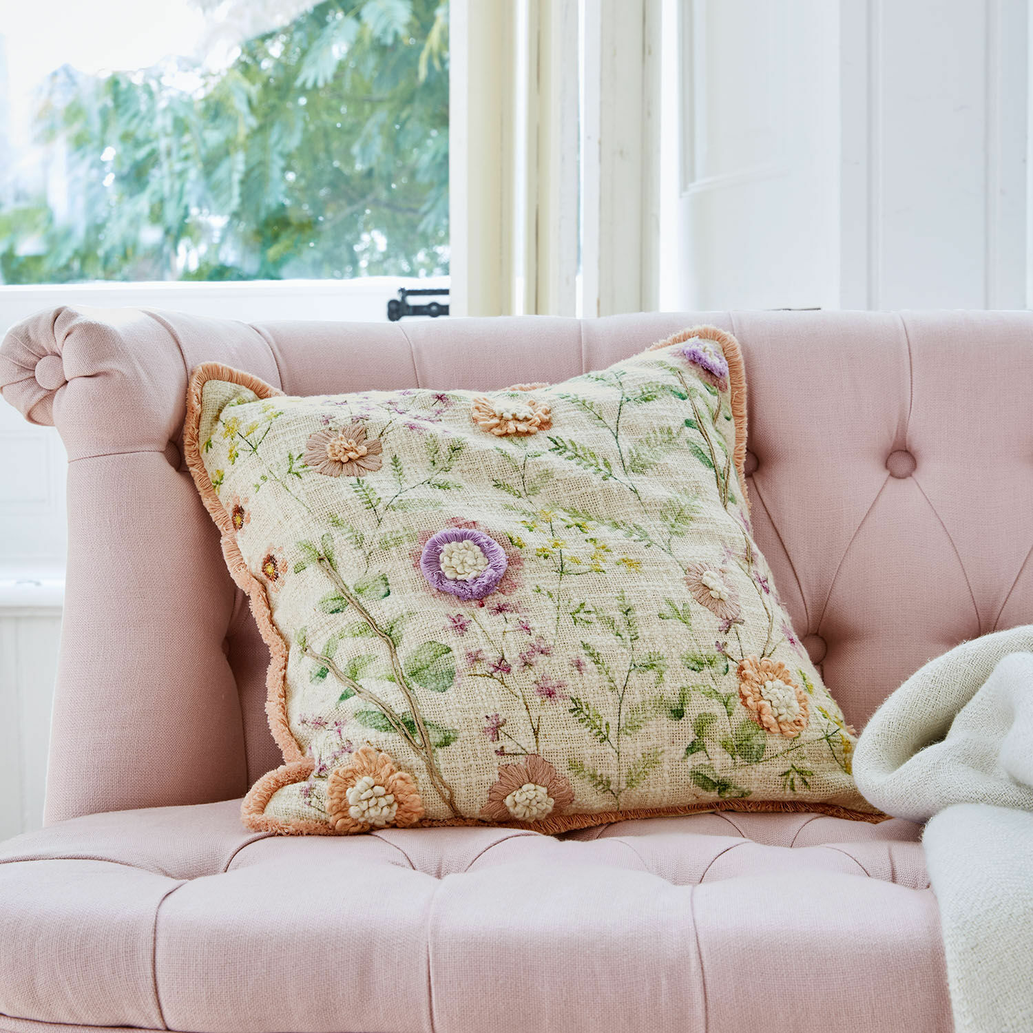 Kissenhülle Lailah Dekoratives Kissen mit Blumenstickerei auf rosa gepolstertem Sofa in hellem Raum