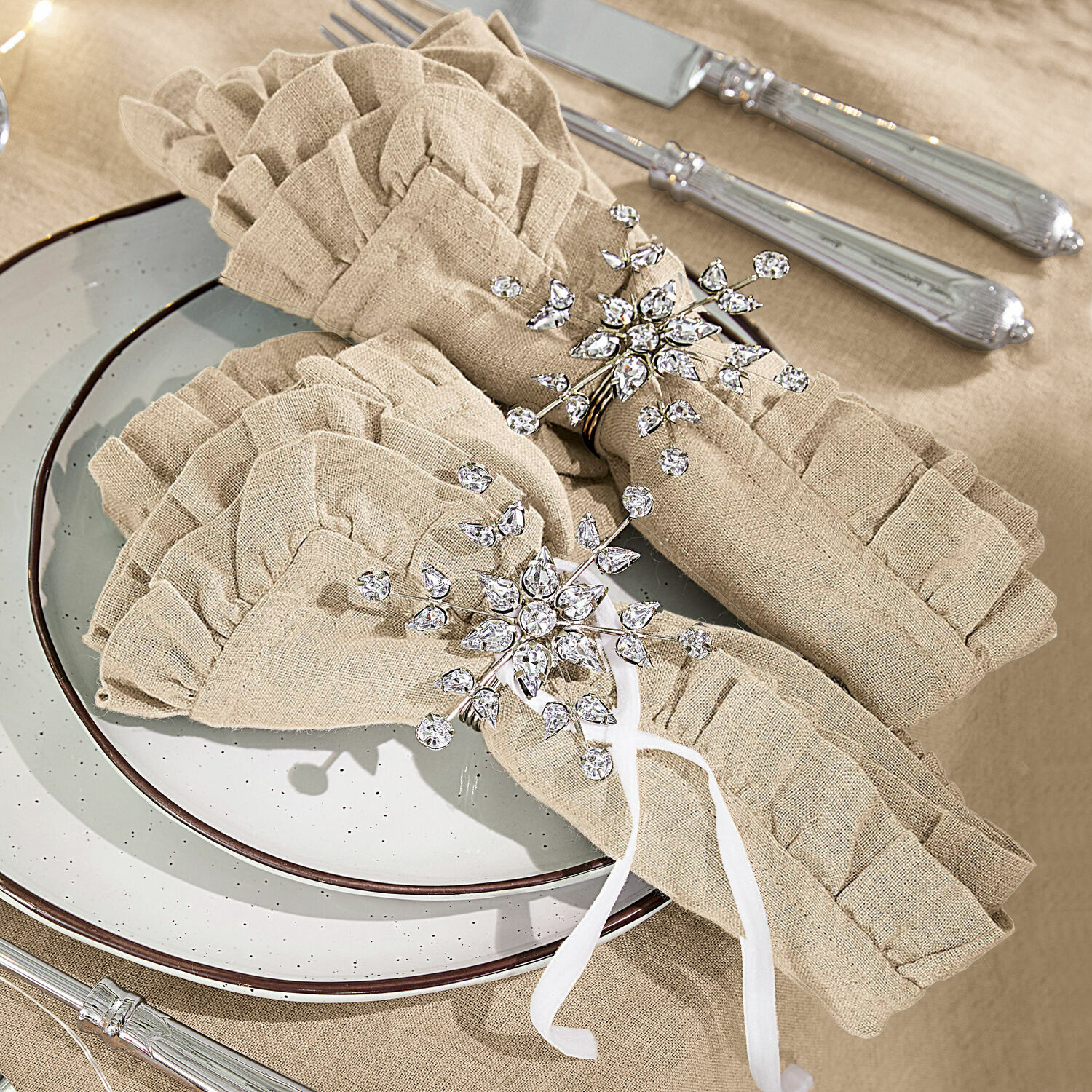Serviettenring 2er Set Sophie Beige Leinen-Servietten mit Rüschen und funkelnden Kristall-Serviettenringen auf gedecktem Tisch