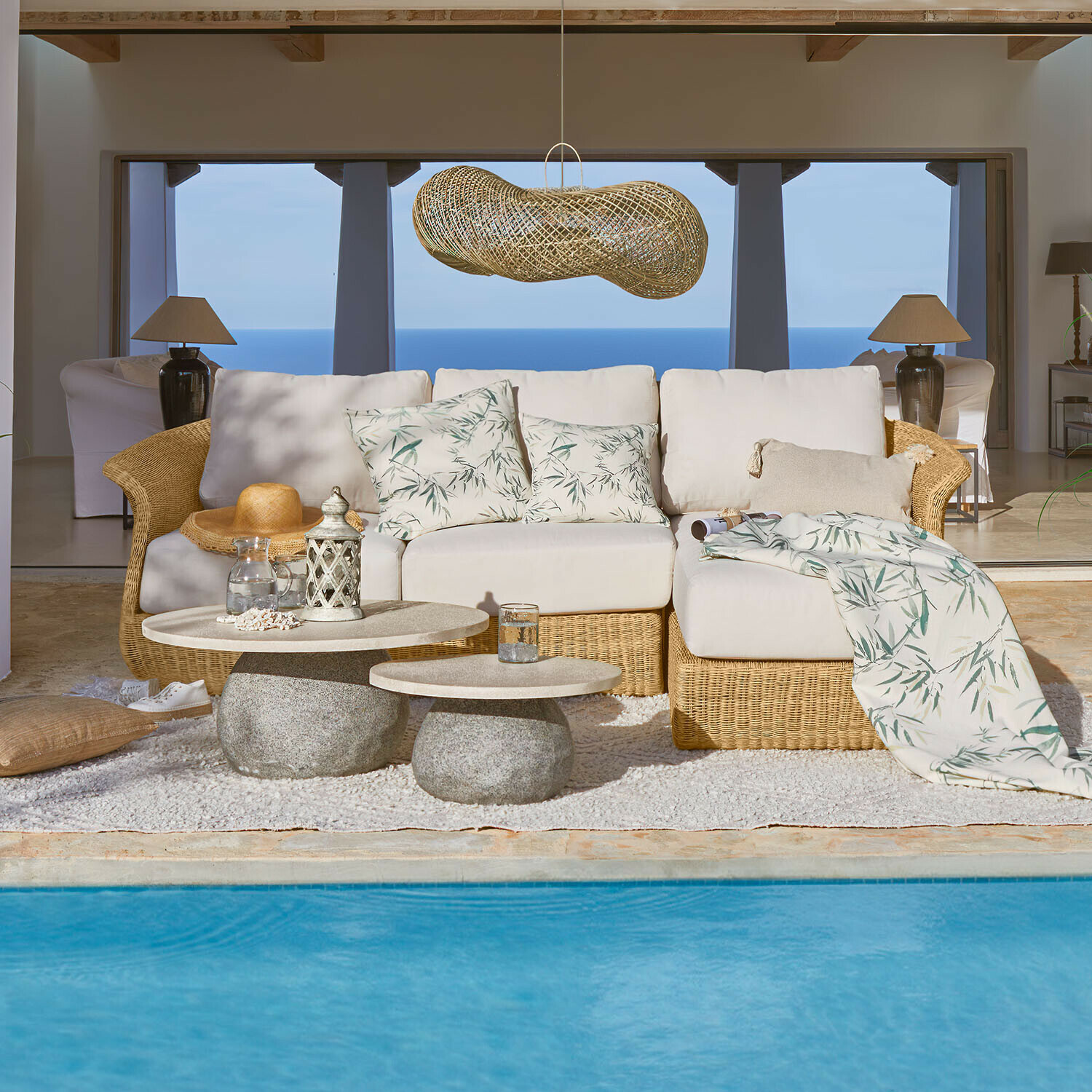 Sofa Cassianas Bequeme Rattan-Sofa mit hellen Blattmuster-Kissen am Pool mit Meerblick
