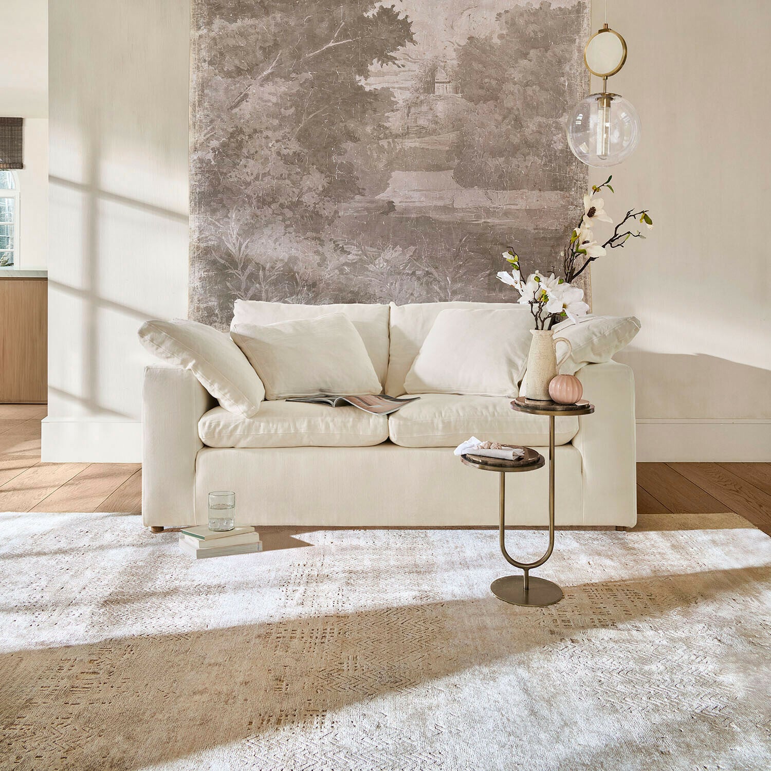 Sofa Everholt Beige Sofa mit weichen Kissen vor Wand mit dekorativem Wandbild und Beistelltisch mit Blumen