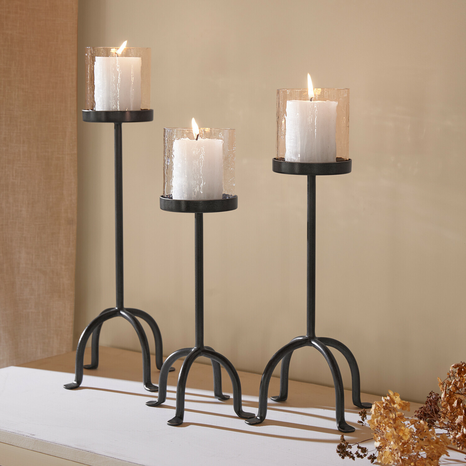 Kerzenständer 3er Set Tanbira Dreiteiliges Set aus schwarzen Metall-Kerzenhaltern mit weißen Kerzen und strukturierten Glasaufsätzen