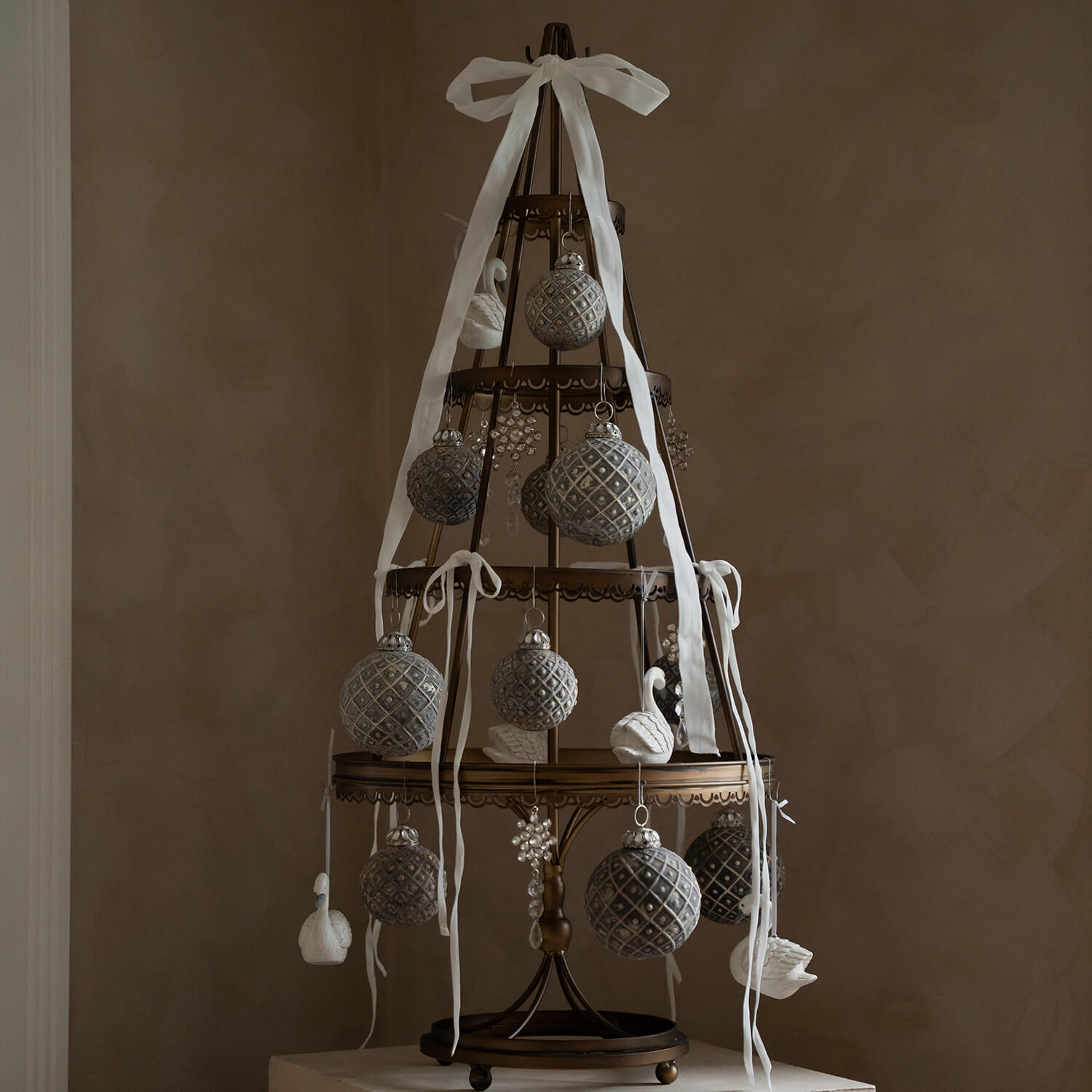 Dekorativer Metall-Weihnachtsbaum mit grauen Kugeln und weißen Bändern im Vintage-Stil