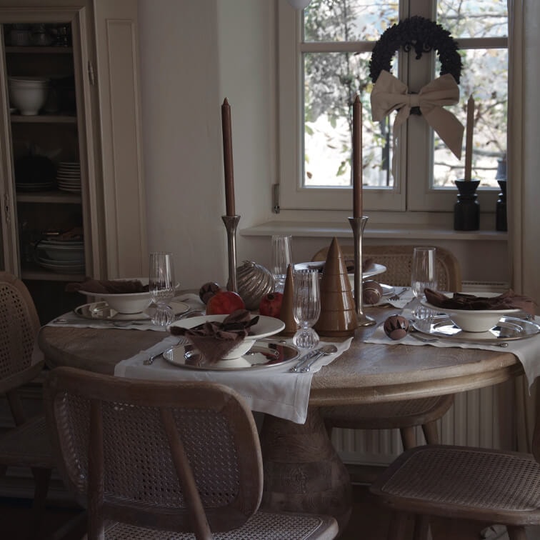 Rustikaler Holztisch mit Weihnachtsdekoration und braunen Kerzen in gemütlichem Esszimmer