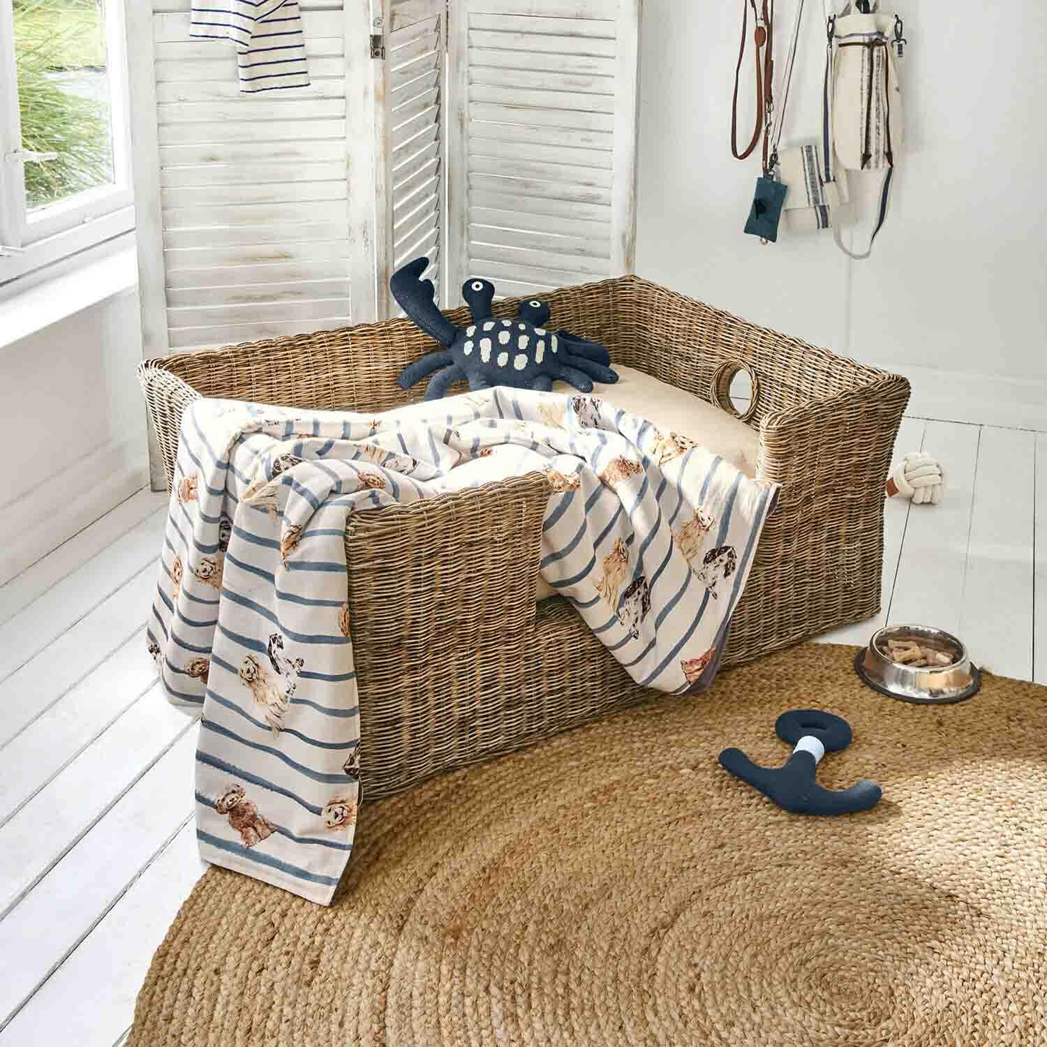 Wicker Hundebett mit beigem Kissen, gestreifter Decke mit Hunde-Motiv, Spielzeug und Futternapf