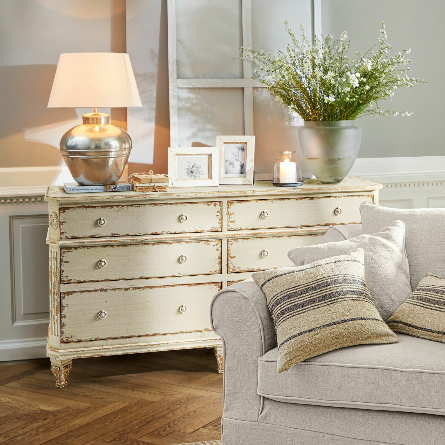 Kommode Commeren Kremfarbene Holzkommode im Vintage-Stil mit Lampe, Bilderrahmen und Dekoration im Wohnzimmer mit beigem Sofa