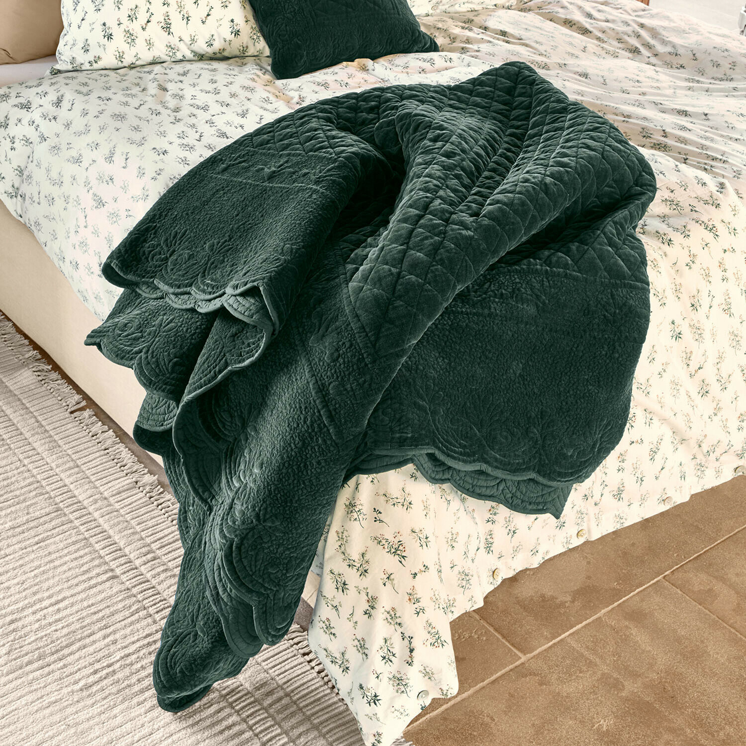 Quilt Lunévois Dunkelgrüne, gesteppte Decke aus weichem Material auf Bett mit hell geblümter Bettwäsche