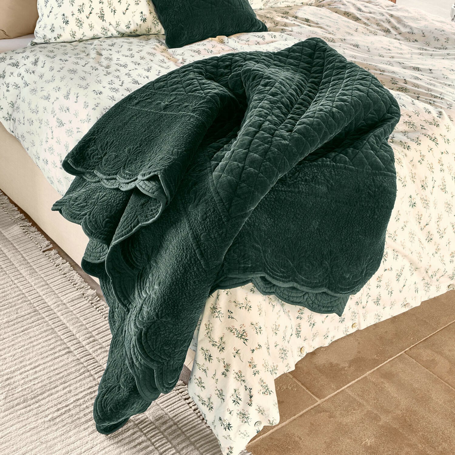 Quilt Lunévois Dunkelgrüne, gesteppte Decke aus weichem Material auf Bett mit hell geblümter Bettwäsche