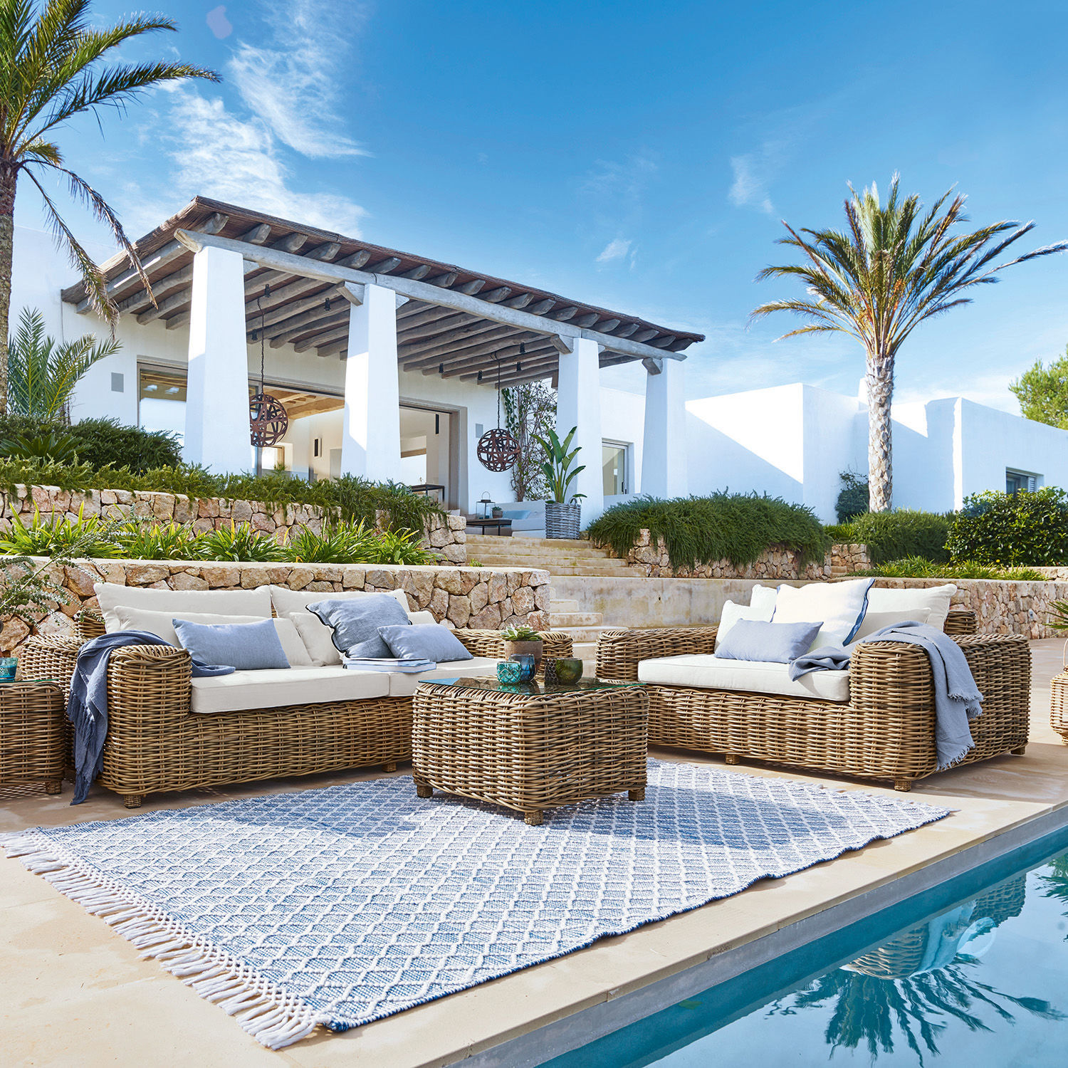 Sitzgruppe Camas Gartenmöbel-Set aus natürlichem Rattan mit cremefarbenen Polstern am Poolrand
