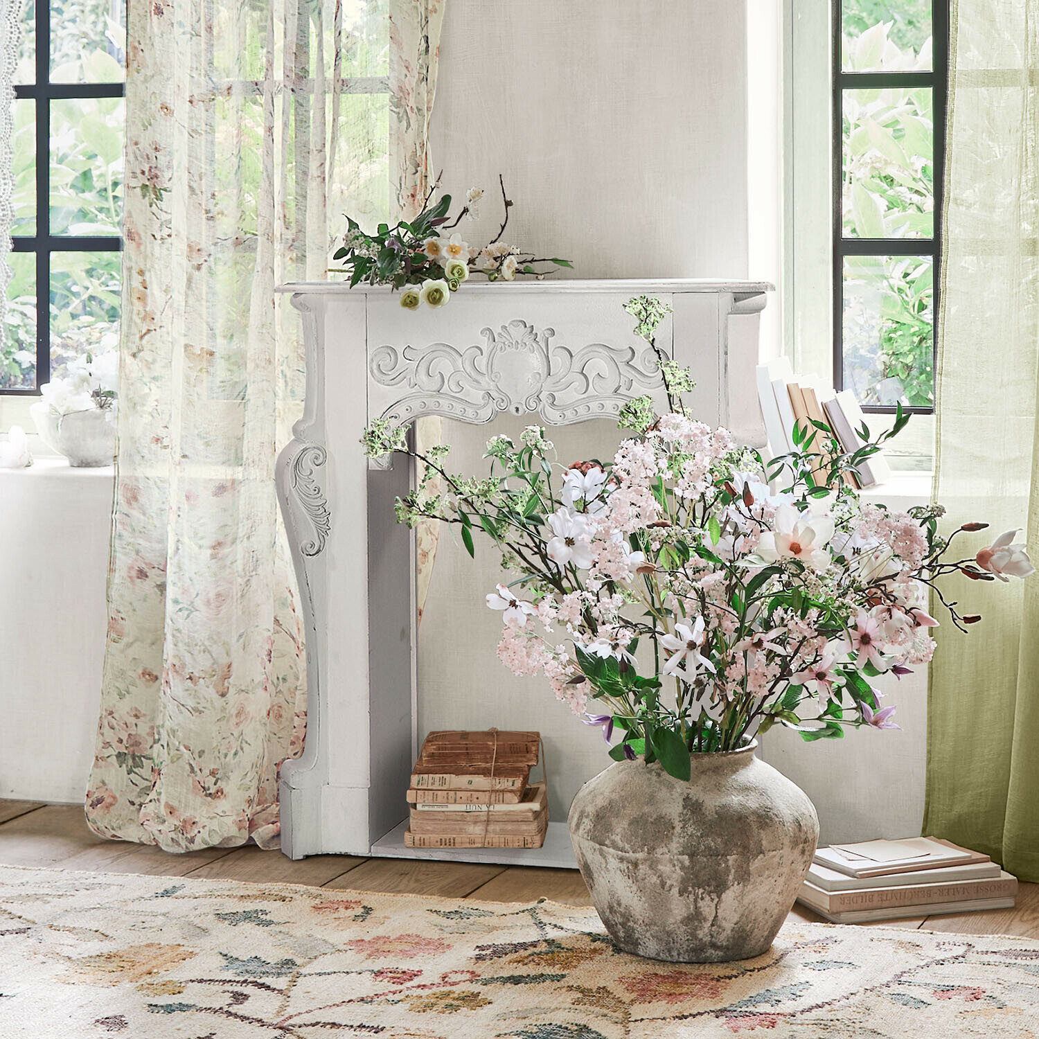 Kaminkonsole Emporia Große graue Keramikvase mit rosa und weißen Blumen vor einem hellen Raum mit dekorativem Kamin