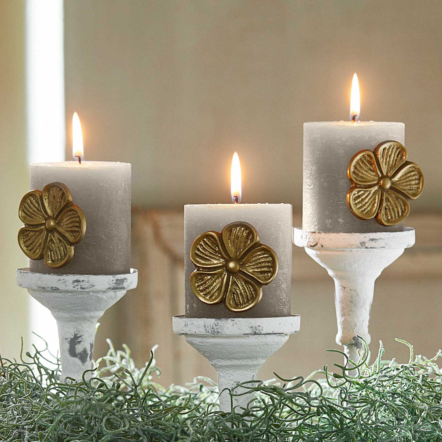 Deko-Pin 3er Set Olevir Drei graue Kerzen mit goldener Blumenverzierung auf weißen Kerzenhaltern mit grünem Blattwerk