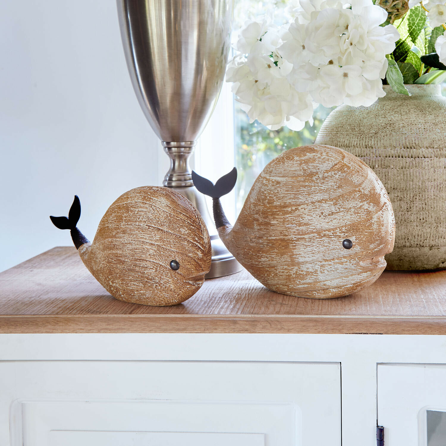 Holz-Dekorationen in Form von Walen in Naturfarbe mit schwarzem Schwanz auf hellem Tisch