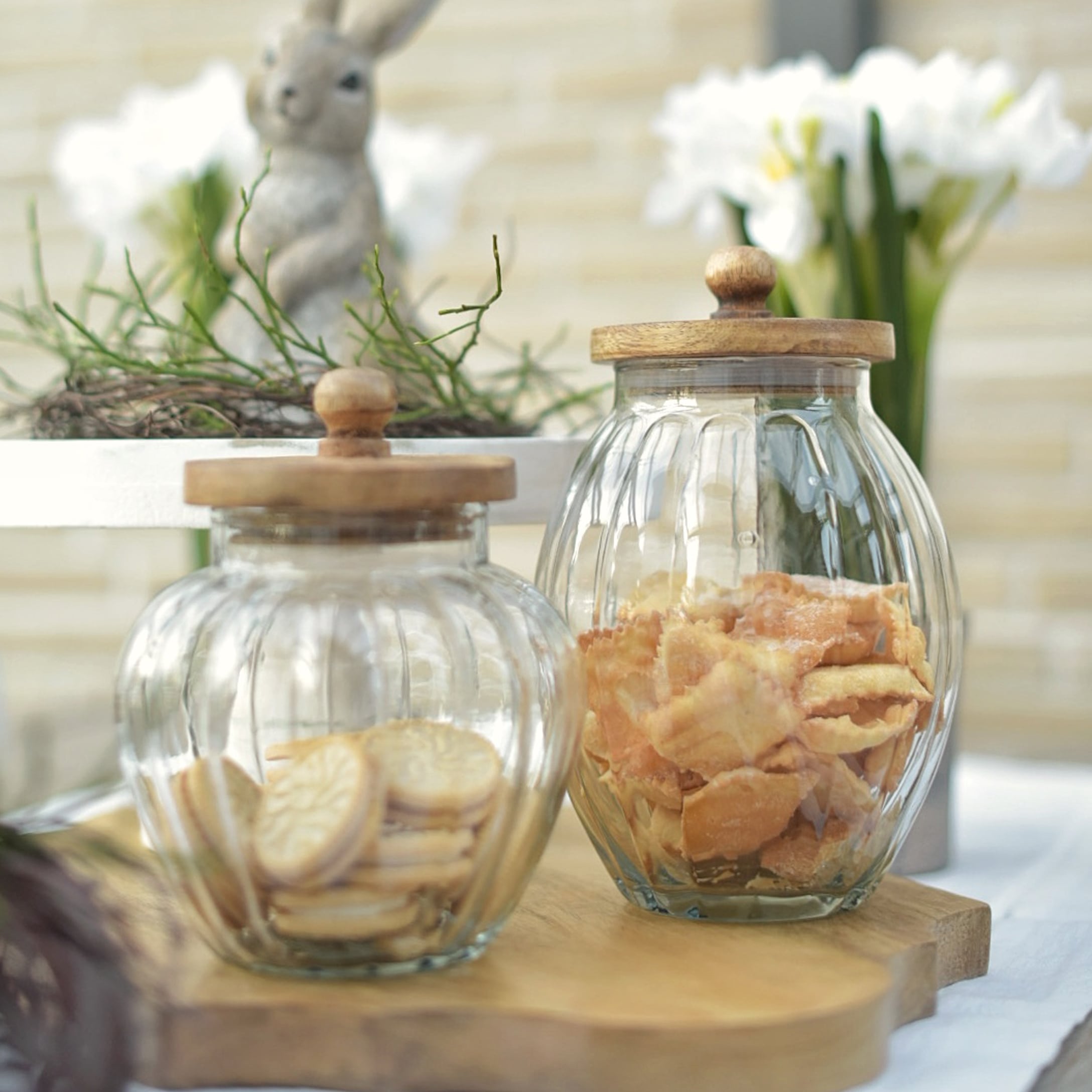 Gläser mit Holzdeckeln gefüllt mit Keksen, natürliche Osterdekoration aus Glas und Holz