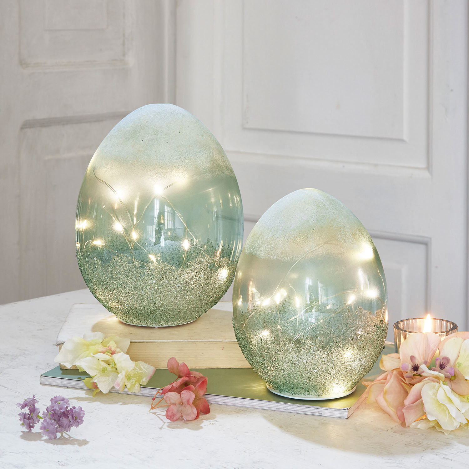 LED-Ei 2er Set Borleos Dekorative grüne Glaseier mit integrierten LED-Lichtern auf Tisch mit Blumen und Kerze