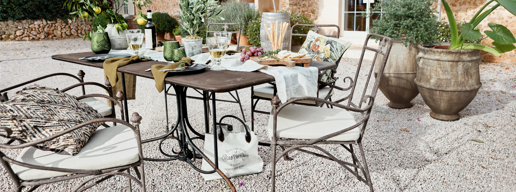 Gartentisch mit Metallstühlen und mediterraner Dekoration auf Kiespatio im Freien