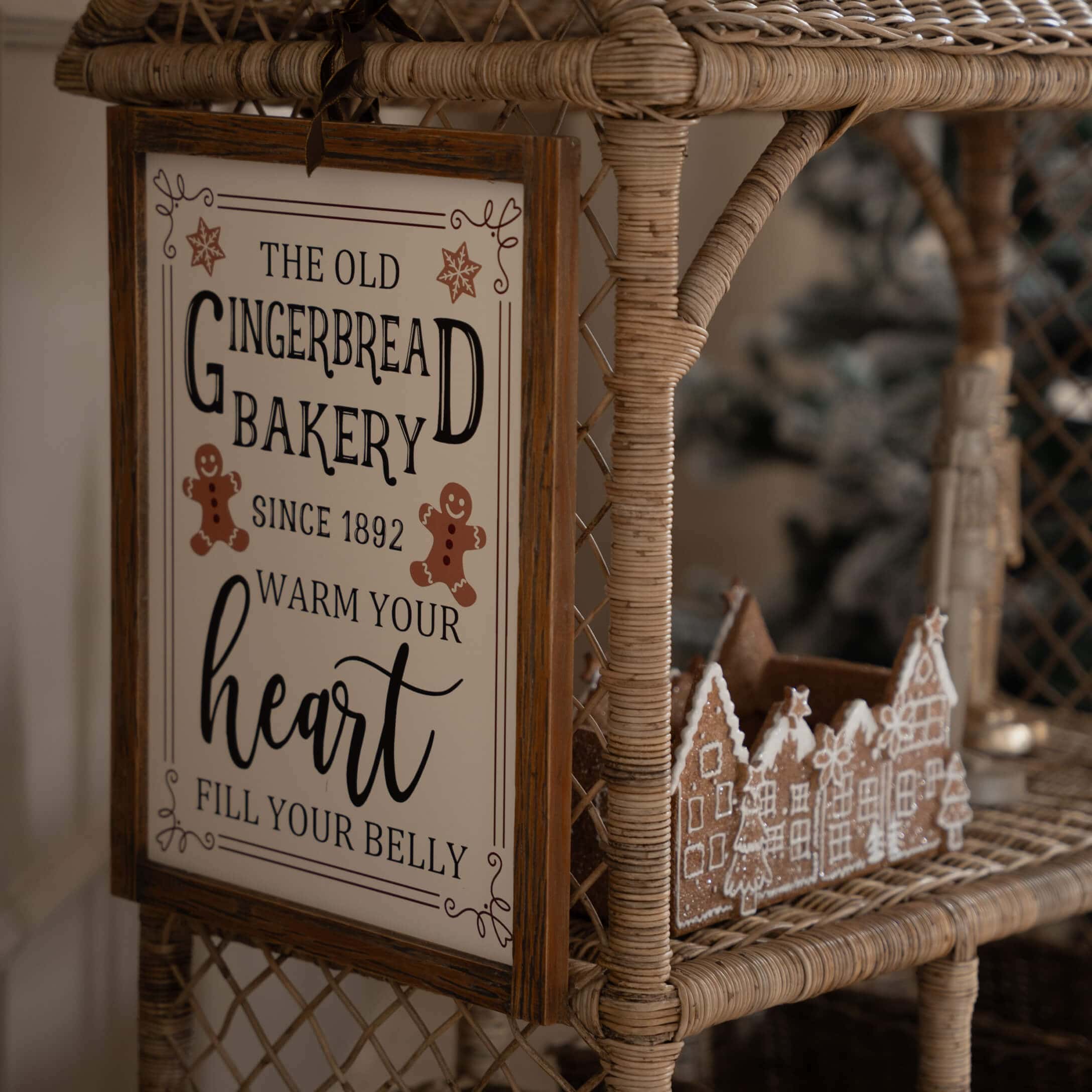 Holzschild mit Aufschrift über Lebkuchenbäckerei auf einem Rattanstuhl mit Lebkuchendorf-Dekor