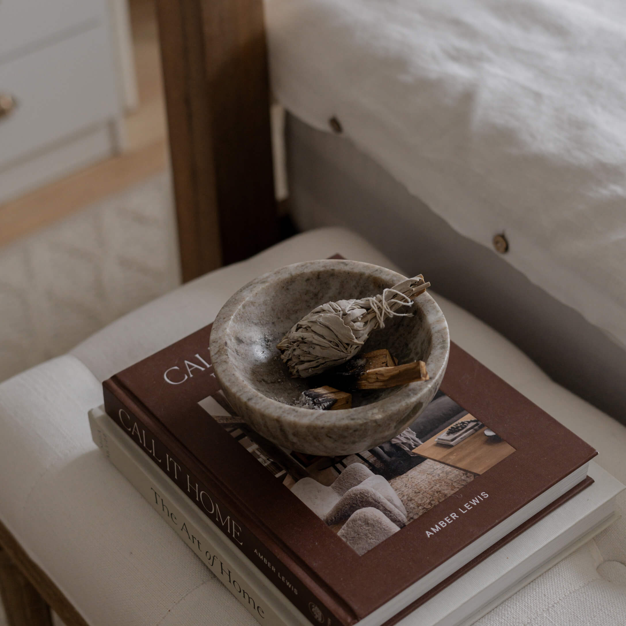 Schale aus grauem Stein mit getrockneten Kräutern auf einem Stapel Wohnbücher
