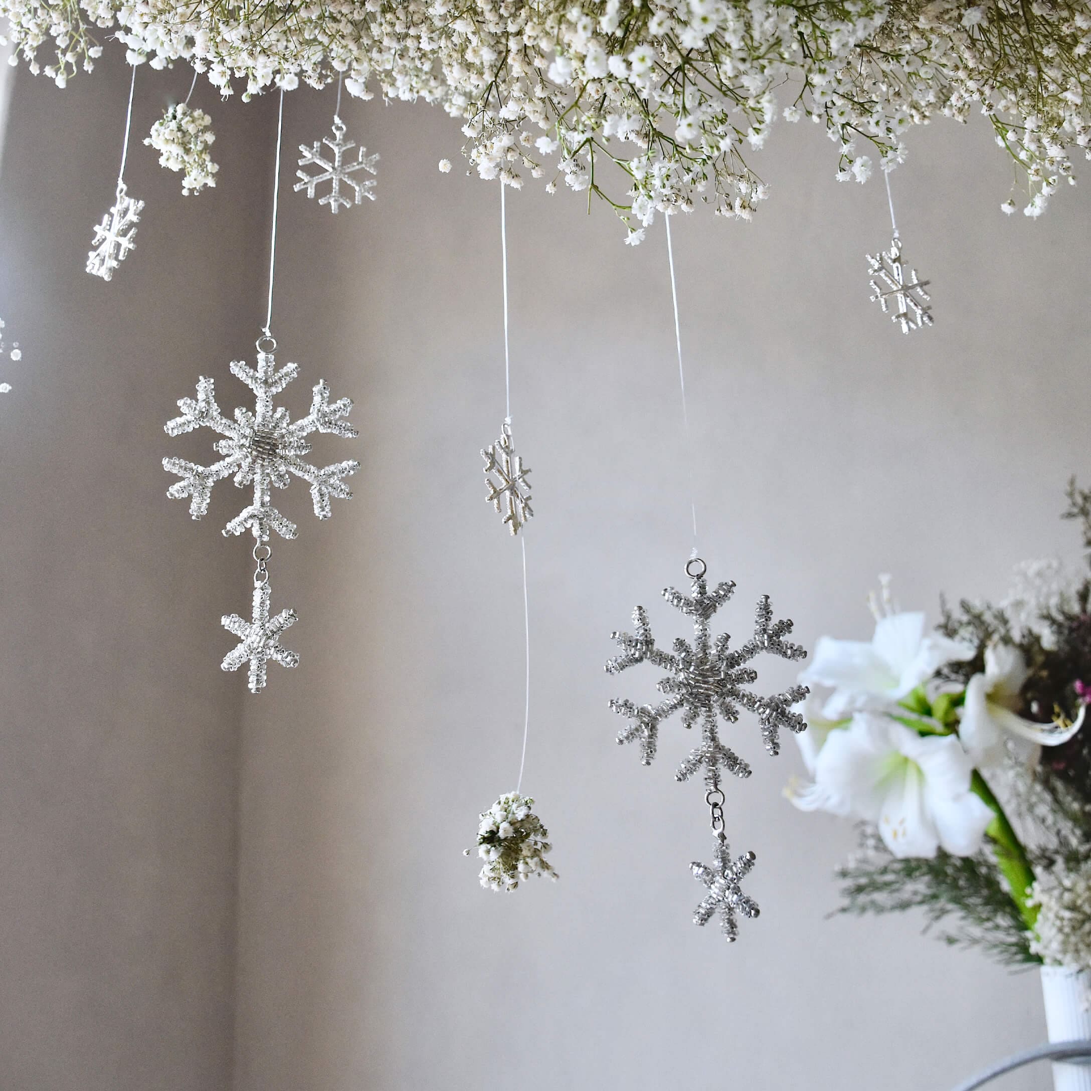 Weiße Schneeflocken- und Blumenanhänger an Fäden, zarte winterliche Raumdekoration