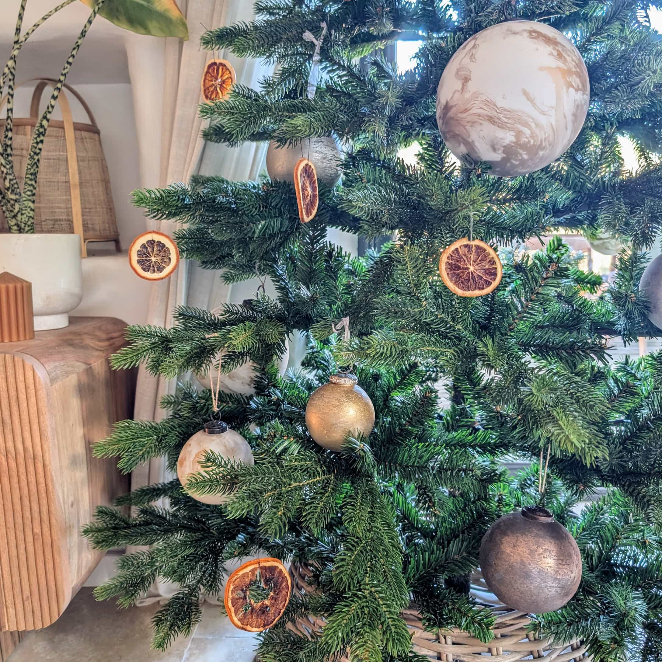 Grüner Weihnachtsbaum mit natürlichen getrockneten Orangenscheiben und gold-beigen Kugeln dekoriert