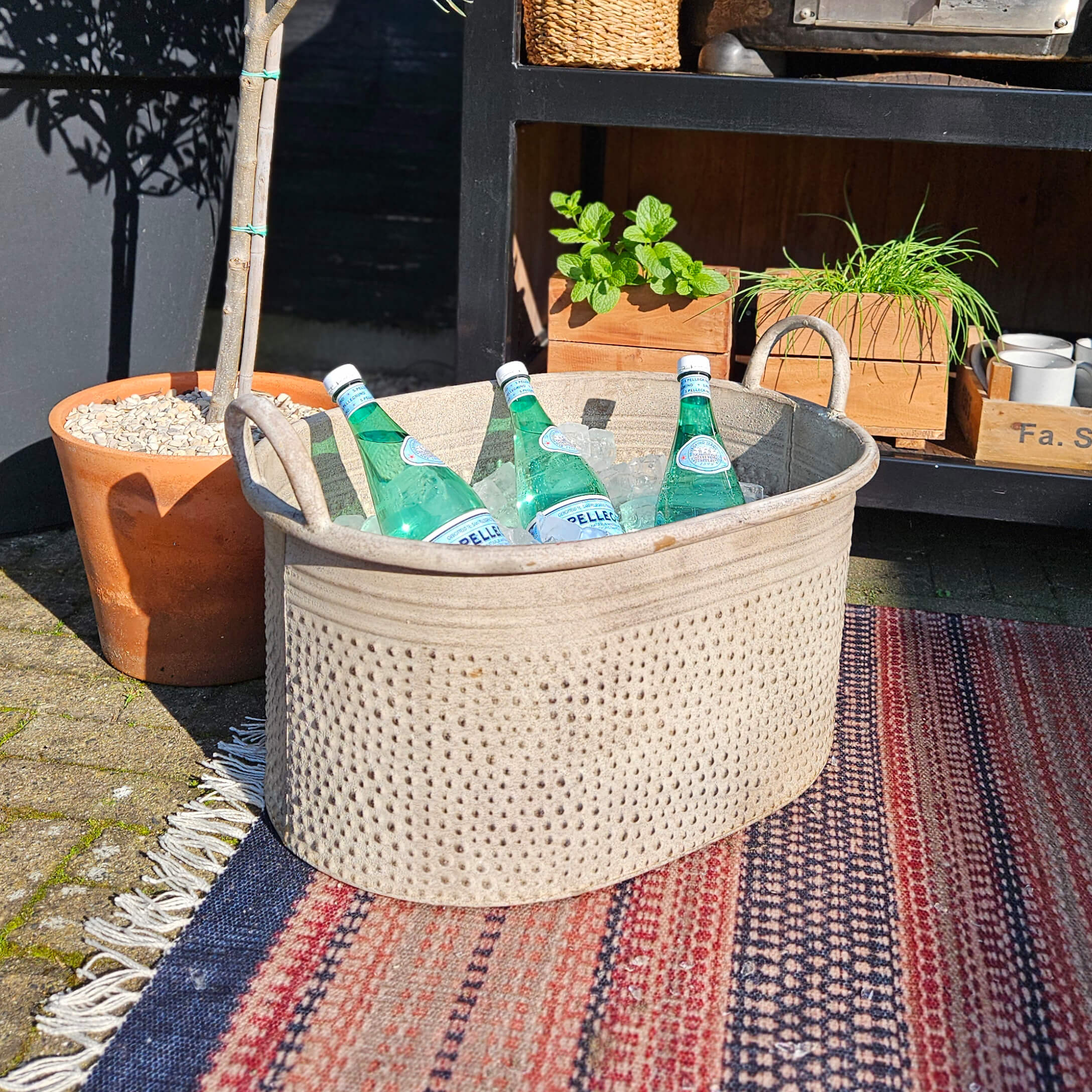 Beiger Stoffkorb mit Griffen, gefüllt mit Mineralwasserflaschen auf Eis, draußen auf Teppich