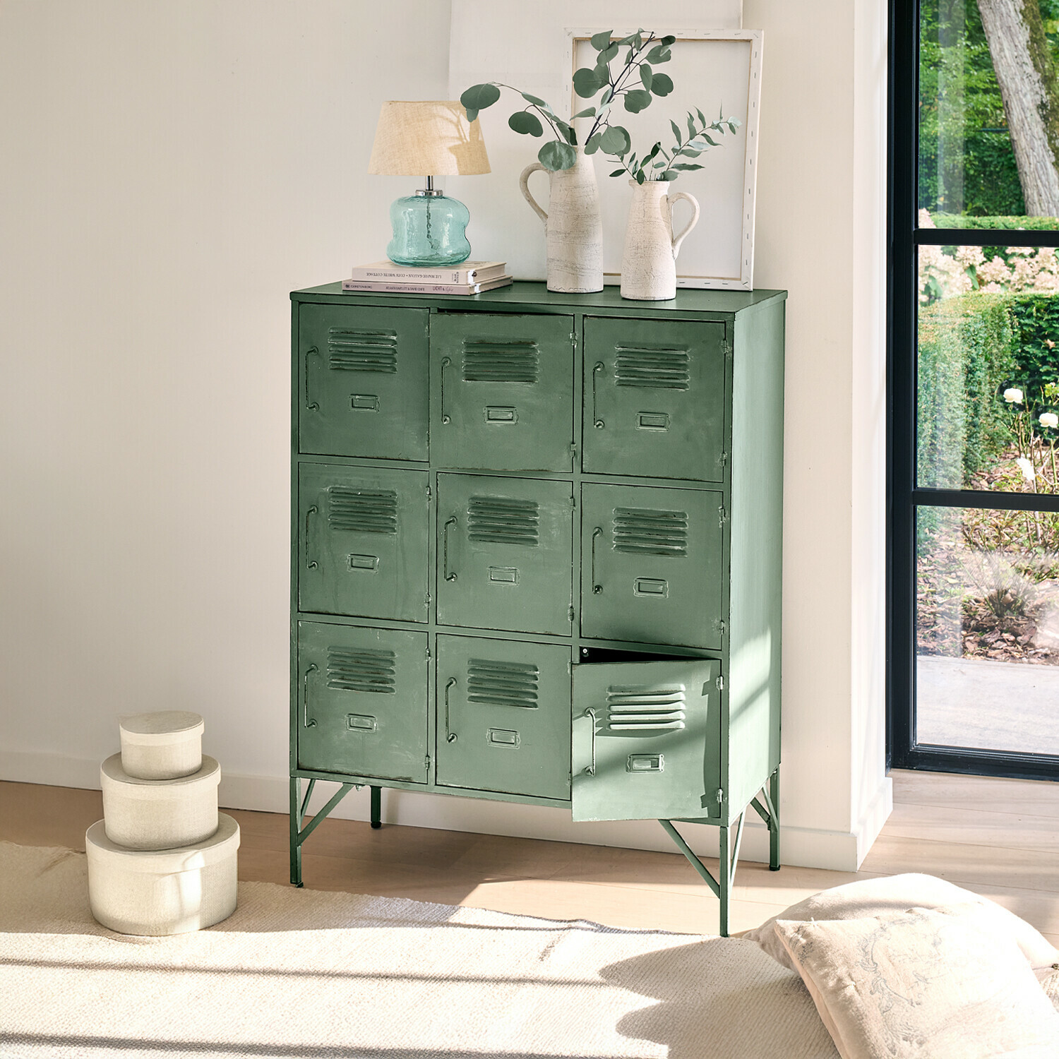 Grüner Metallschrank mit neun Türen und Dekorationen oben in hellem Raum