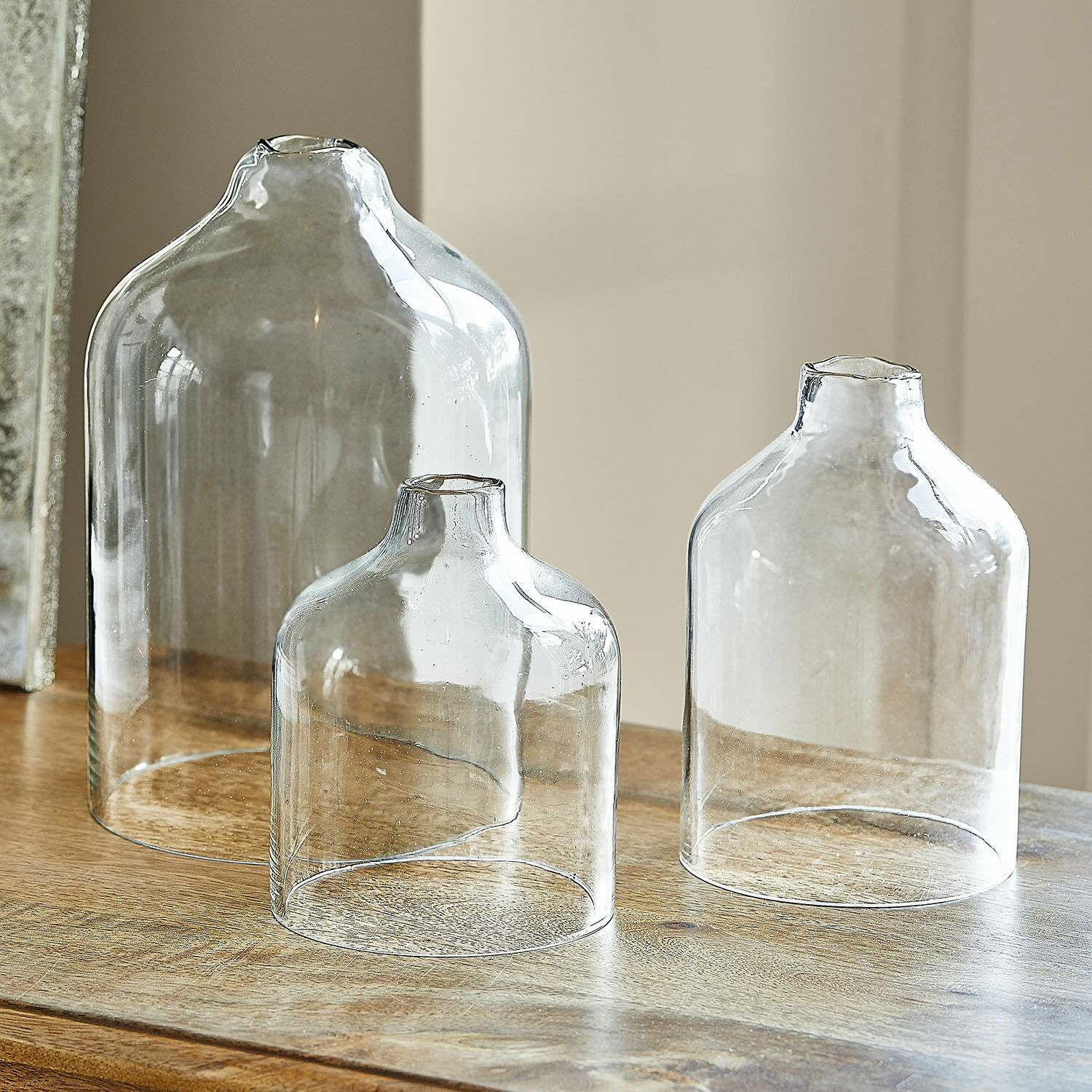 Windlicht 3er Set Xalvent Set aus drei transparenten Glasvasen in verschiedenen Größen auf einem Holztisch