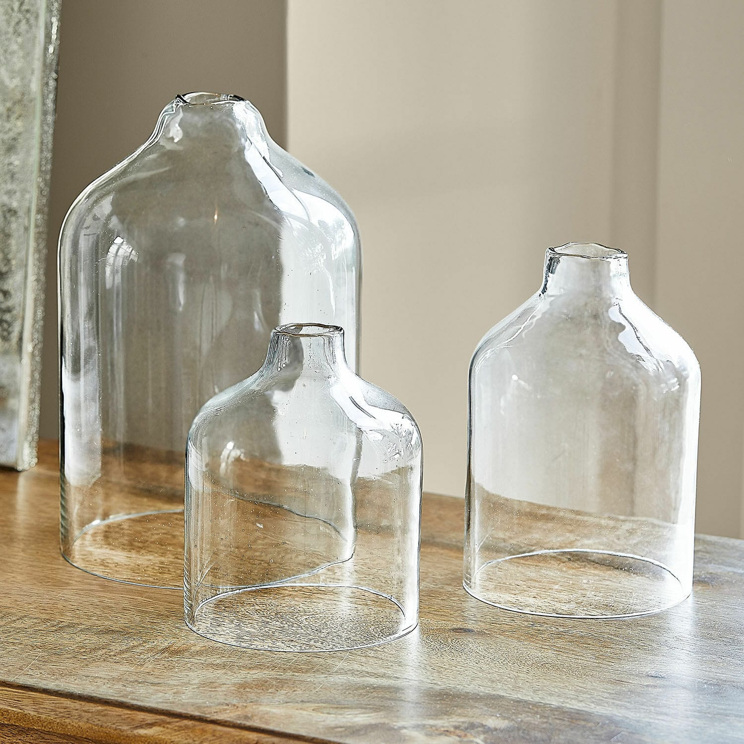 Windlicht 3er Set Xalvent Set aus drei transparenten Glasvasen in verschiedenen Größen auf einem Holztisch