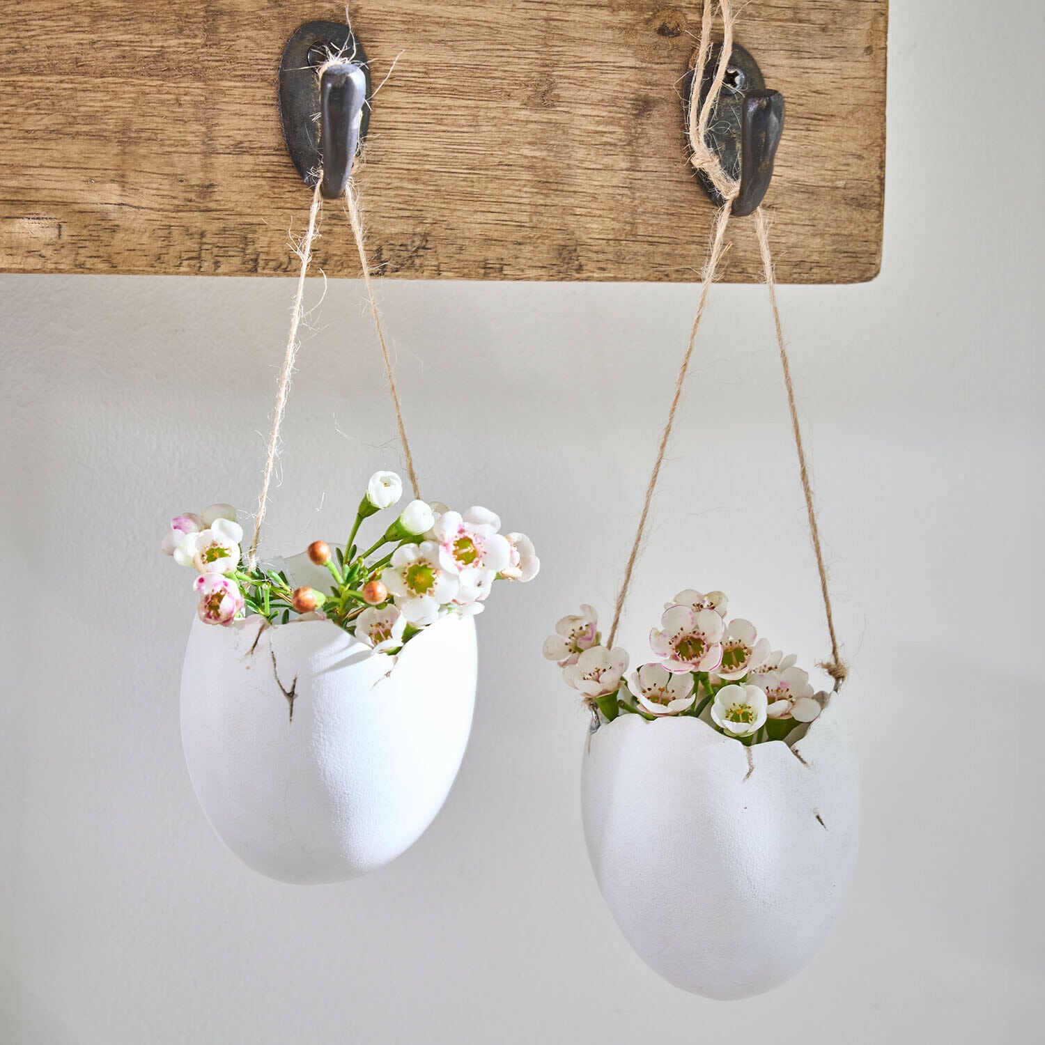Hängevase 2er Set Nalena Zwei weiße Keramikblumentöpfe in Ei-Form mit Blumen, hängend an einem Holzbrett mit Haken