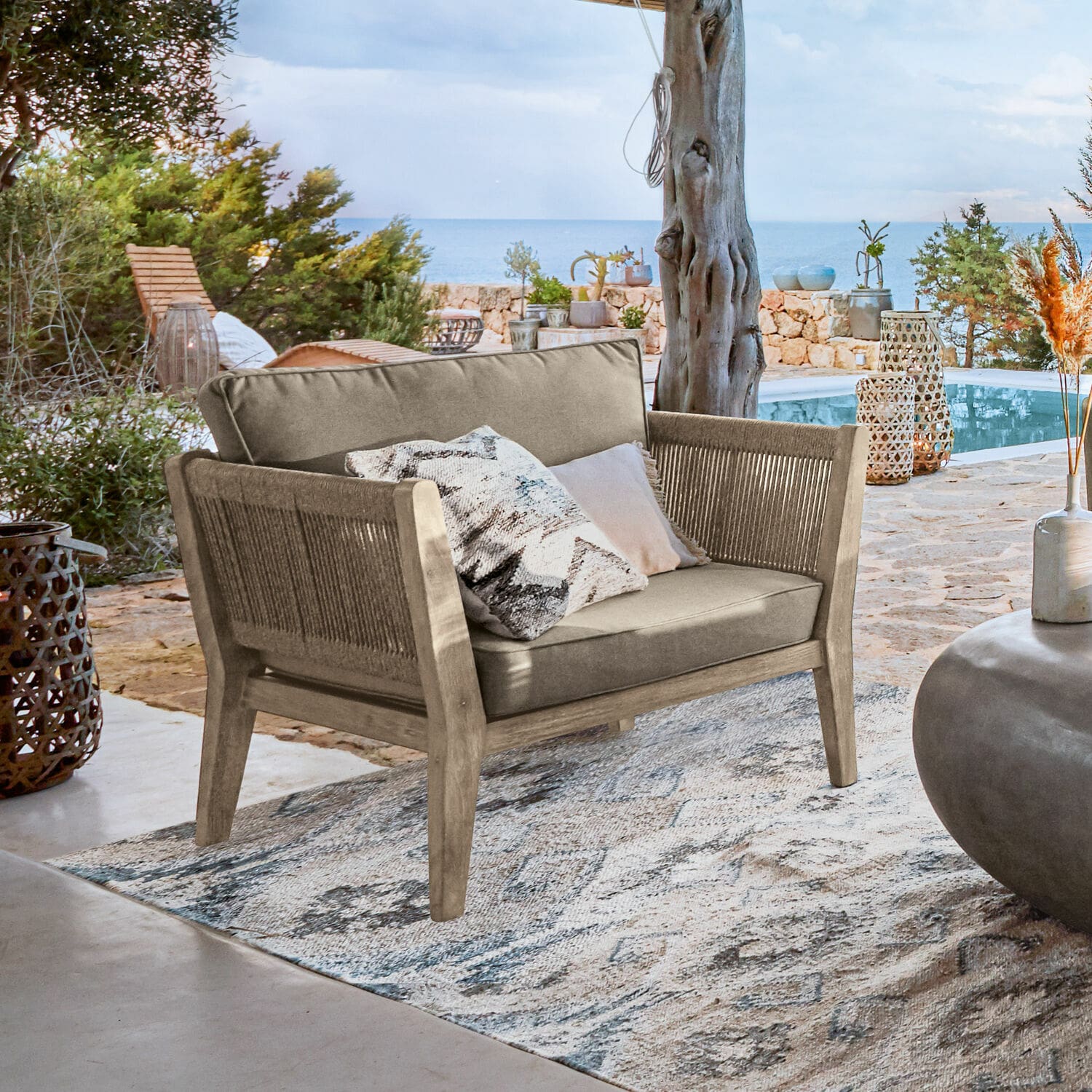 Sessel FSC®-100% Biarritz Outdoor-Sofa aus Holz und beigem Stoff auf Terrasse mit Meerblick